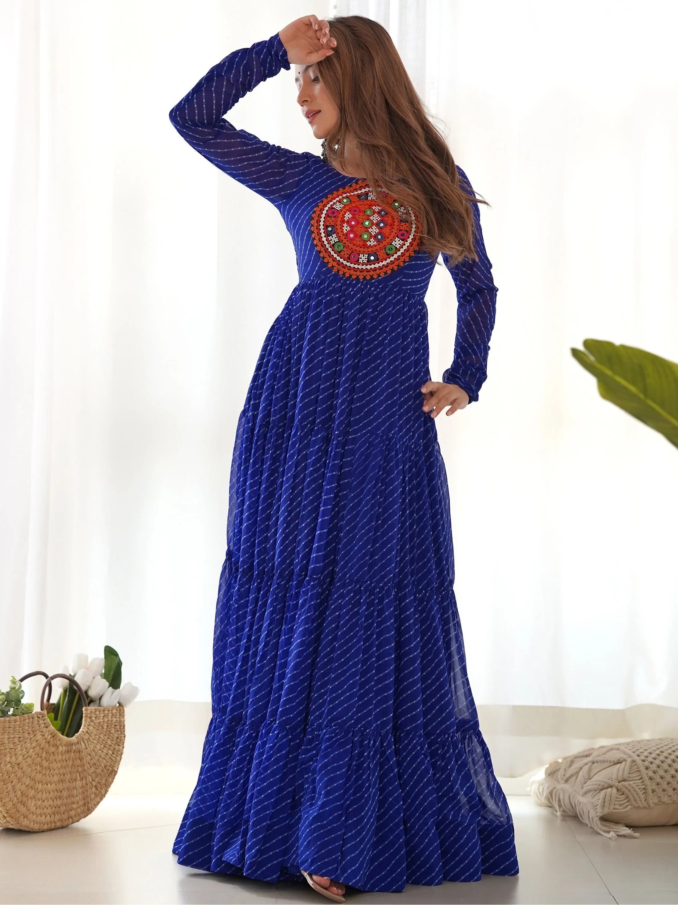 Woman wearing a blue bandhani maxi dress with colorful mirror work yoke, ethnic gown style