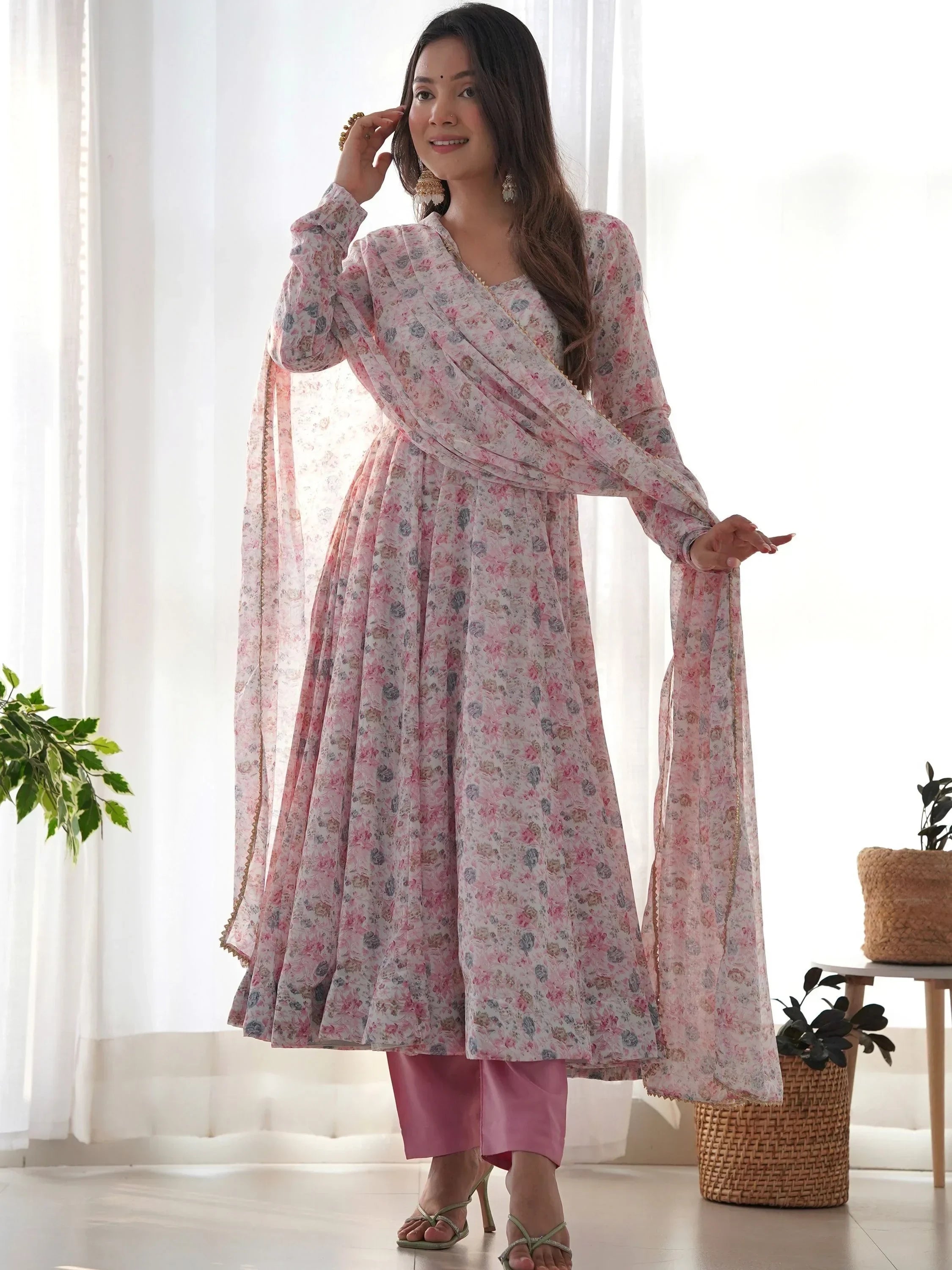 Woman wearing floral print ethnic Anarkali suit with dupatta and pink pants indoors