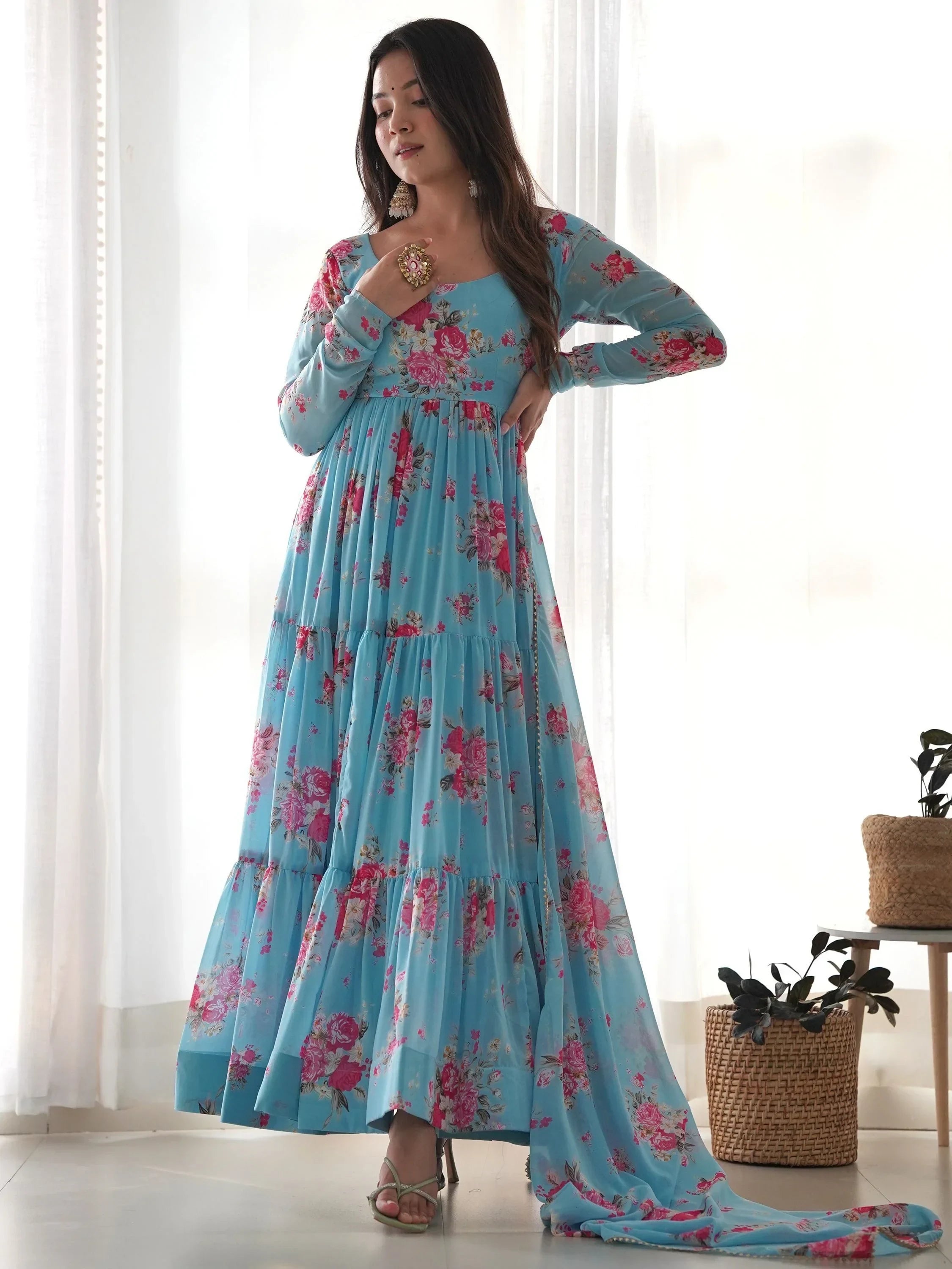 Woman wearing a light blue floral print ethnic gown with long sleeves and flared hem indoors