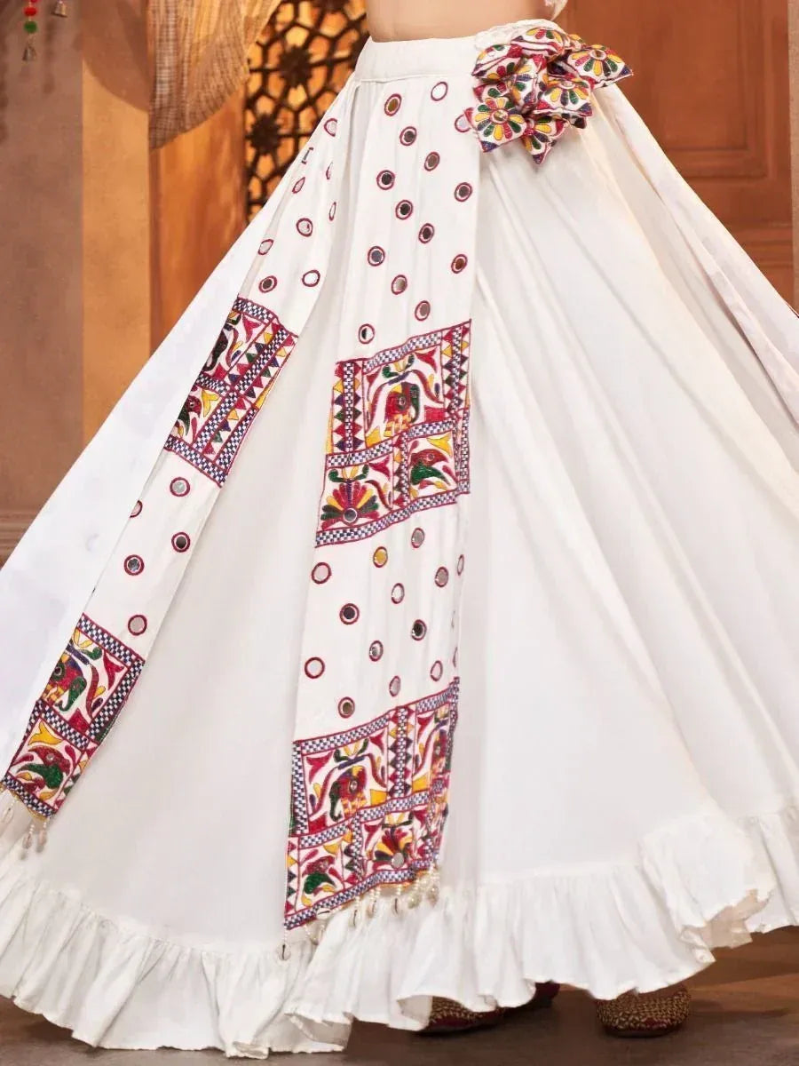 White ethnic skirt with colorful embroidery, mirror work, and ruffled hem for traditional Indian wear