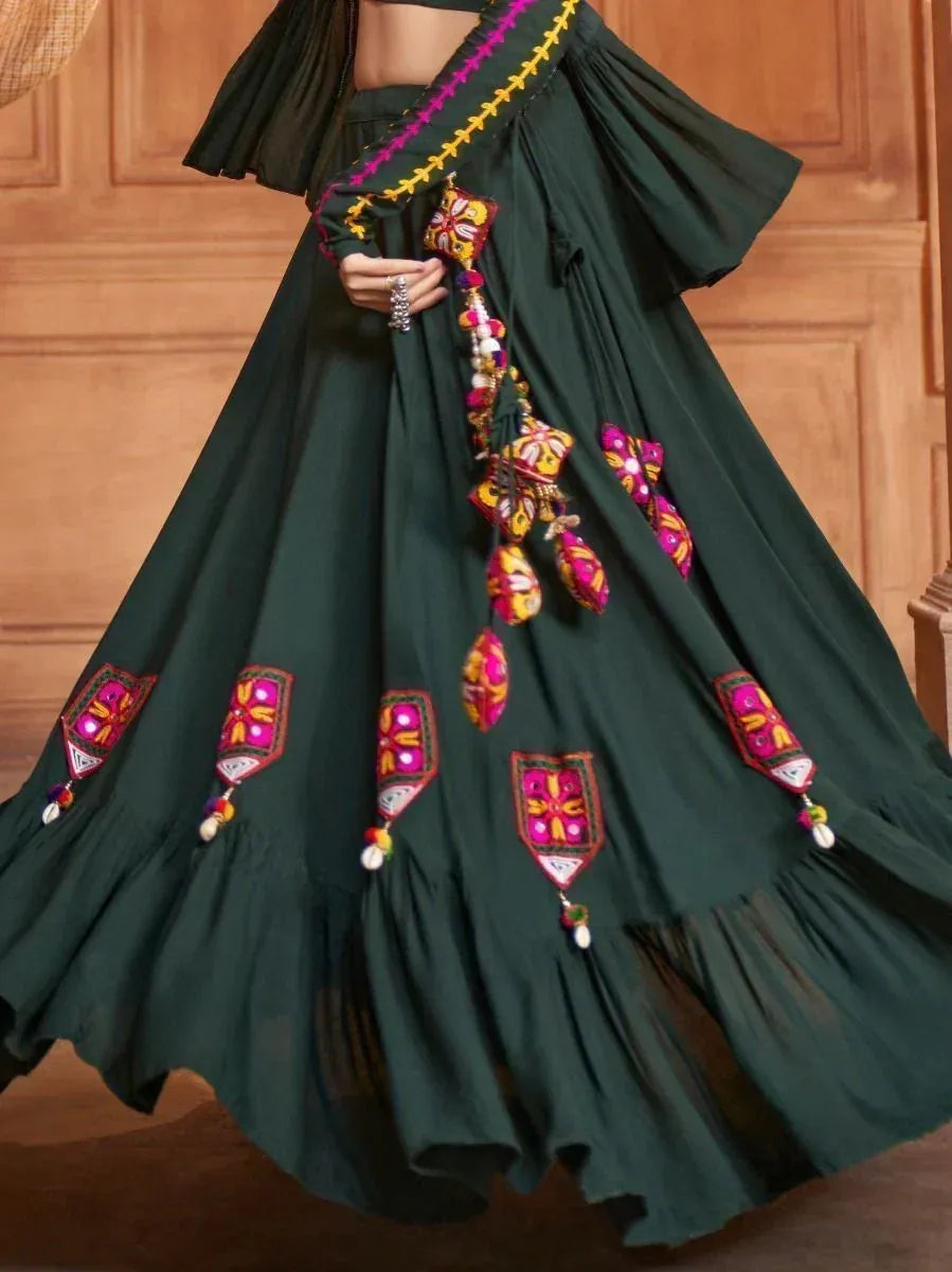 Dark green ethnic lehenga with colorful mirror embroidery and tassels, perfect for Indian festive wear
