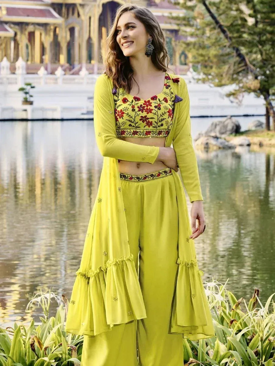 Woman in green floral embroidered crop top with palazzo pants and long shrug by a lake