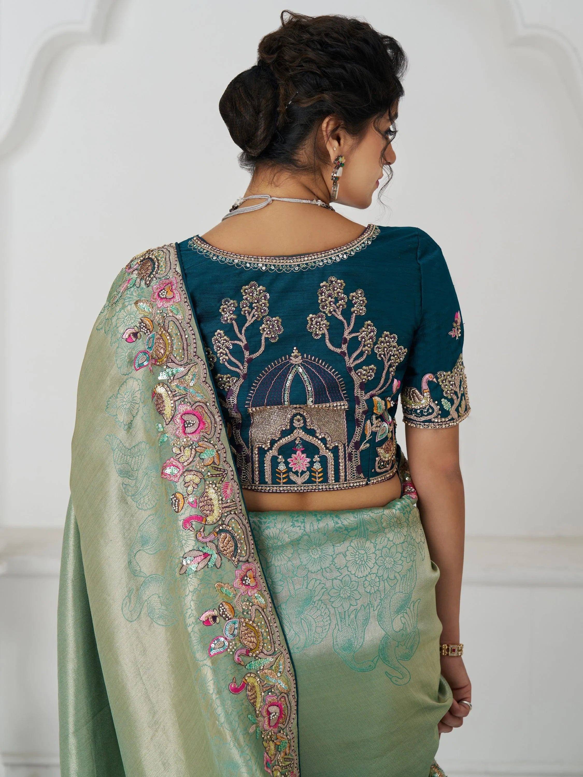 Teal embroidered blouse with floral and peacock motifs, paired with mint green saree, Indian ethnic wear