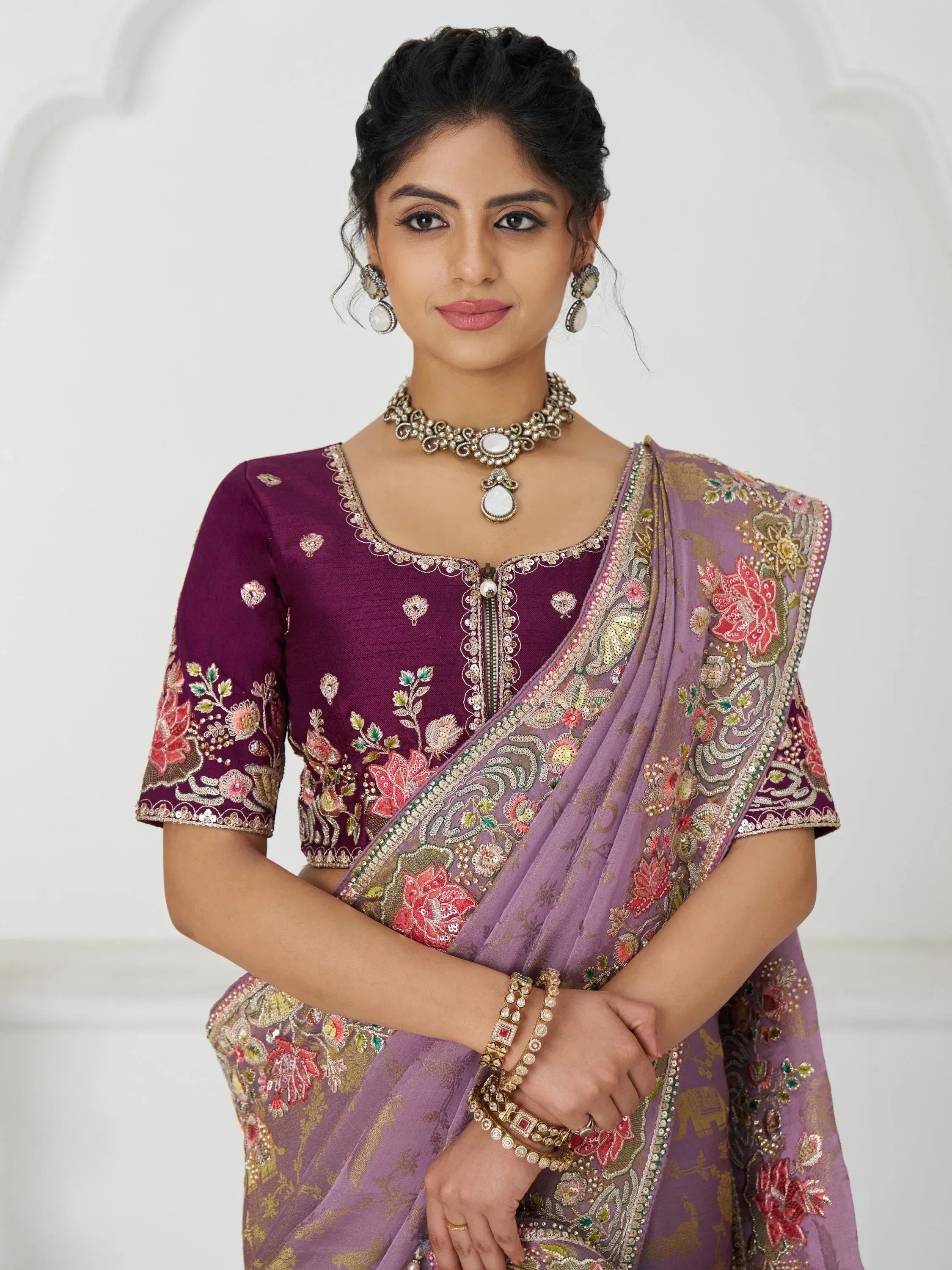 Elegant purple embroidered saree with floral motifs and matching blouse, styled with traditional jewelry for Indian ethnic wear.