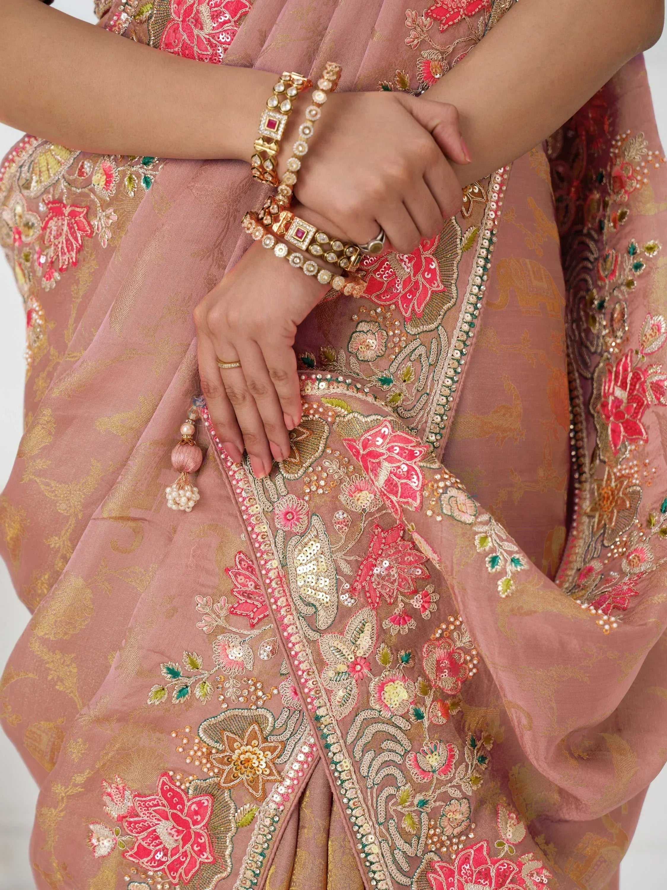 Pink embroidered lehenga choli with floral sequin work and gold detailing, paired with traditional jewelry.