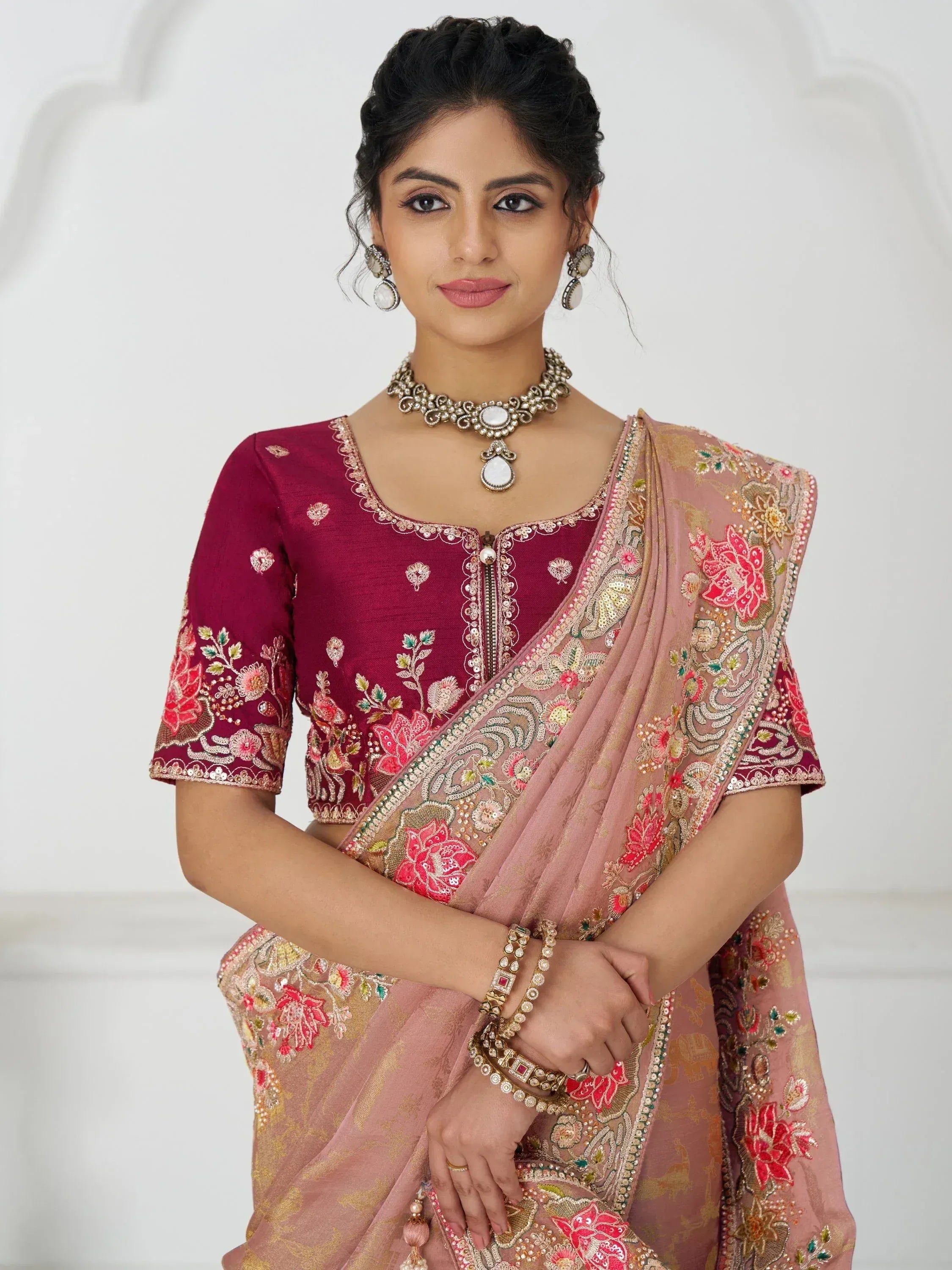 Woman in maroon embroidered blouse with pink floral saree, traditional Indian ethnic wear