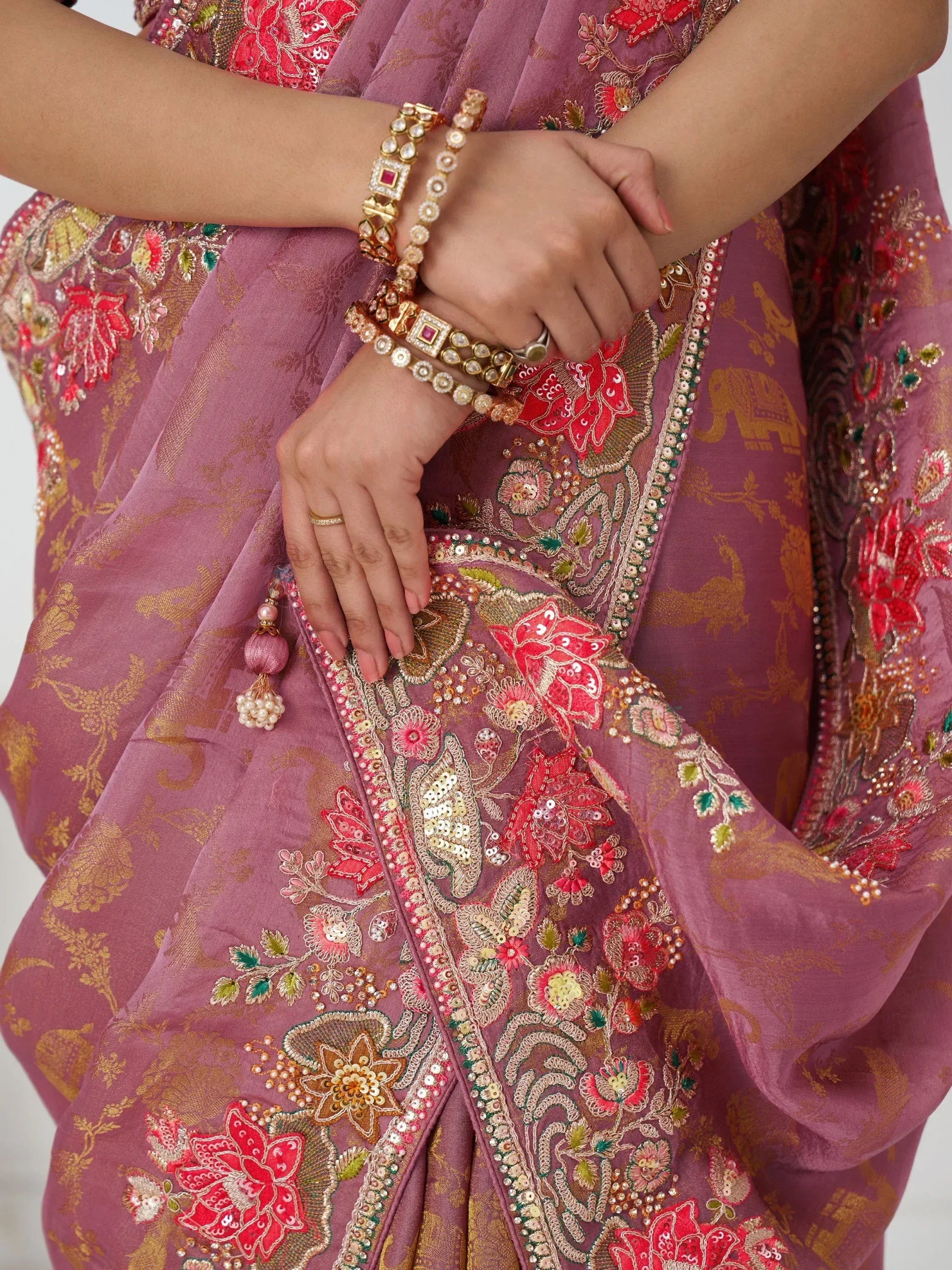 Elegant purple ethnic gown with floral embroidery, sequins, and gold detailing, paired with traditional jewelry.