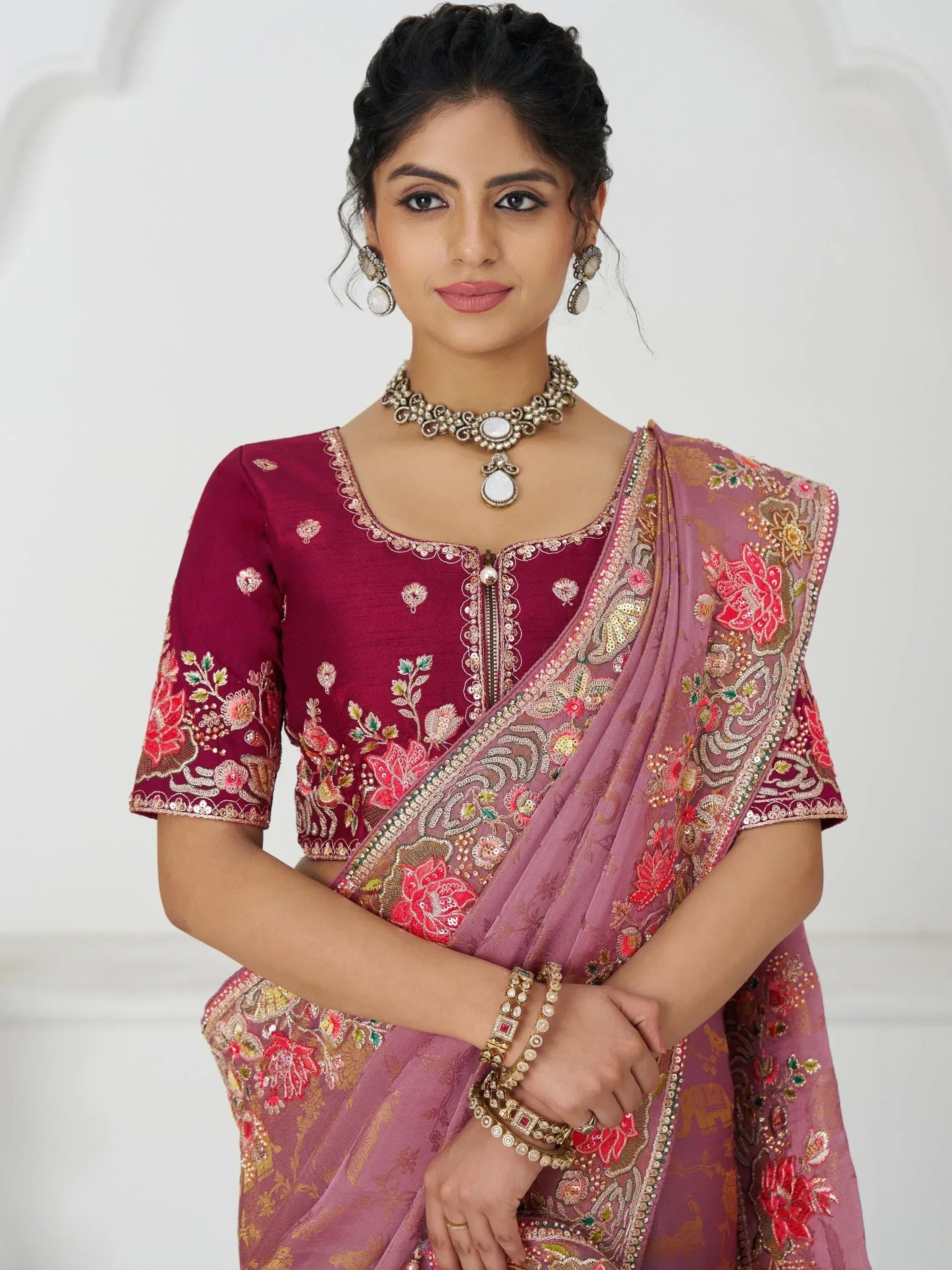 Woman in maroon embroidered blouse and pink floral saree with traditional jewelry