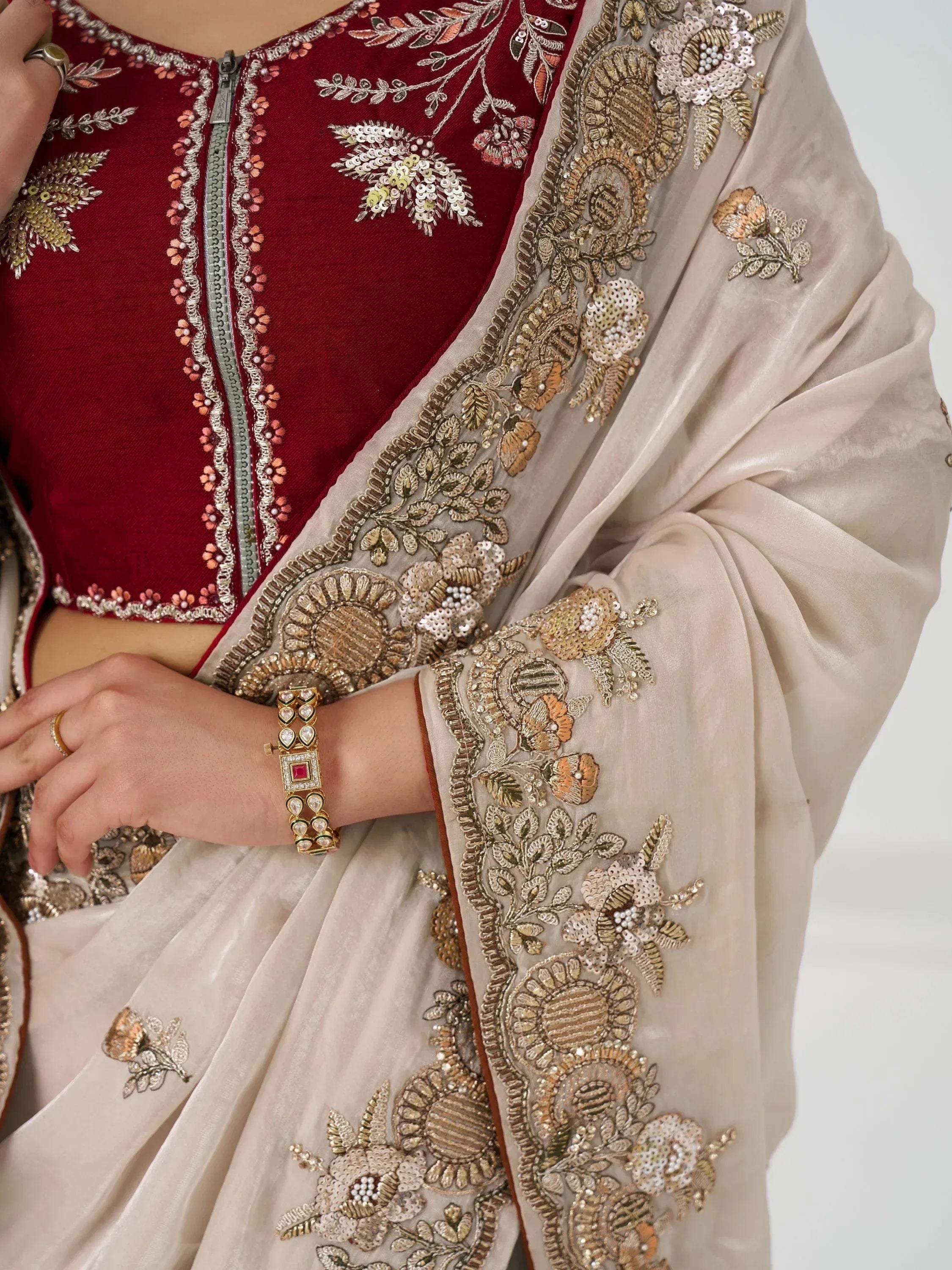 Maroon velvet blouse with gold floral embroidery paired with beige embroidered saree, perfect for Indian ethnic wear.