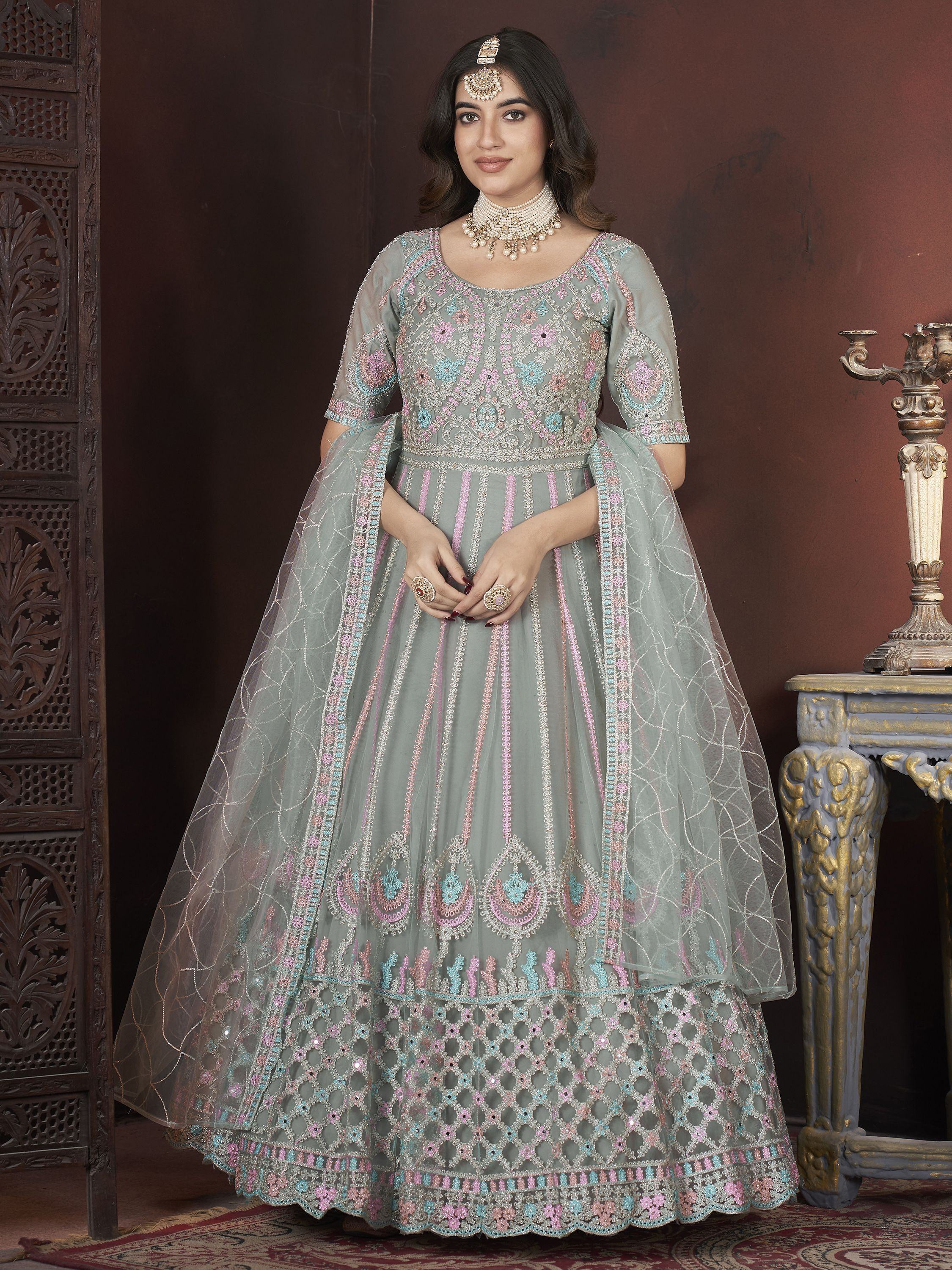 Woman wearing pastel embroidered lehenga choli with dupatta, statement jewelry, Indian ethnic attire