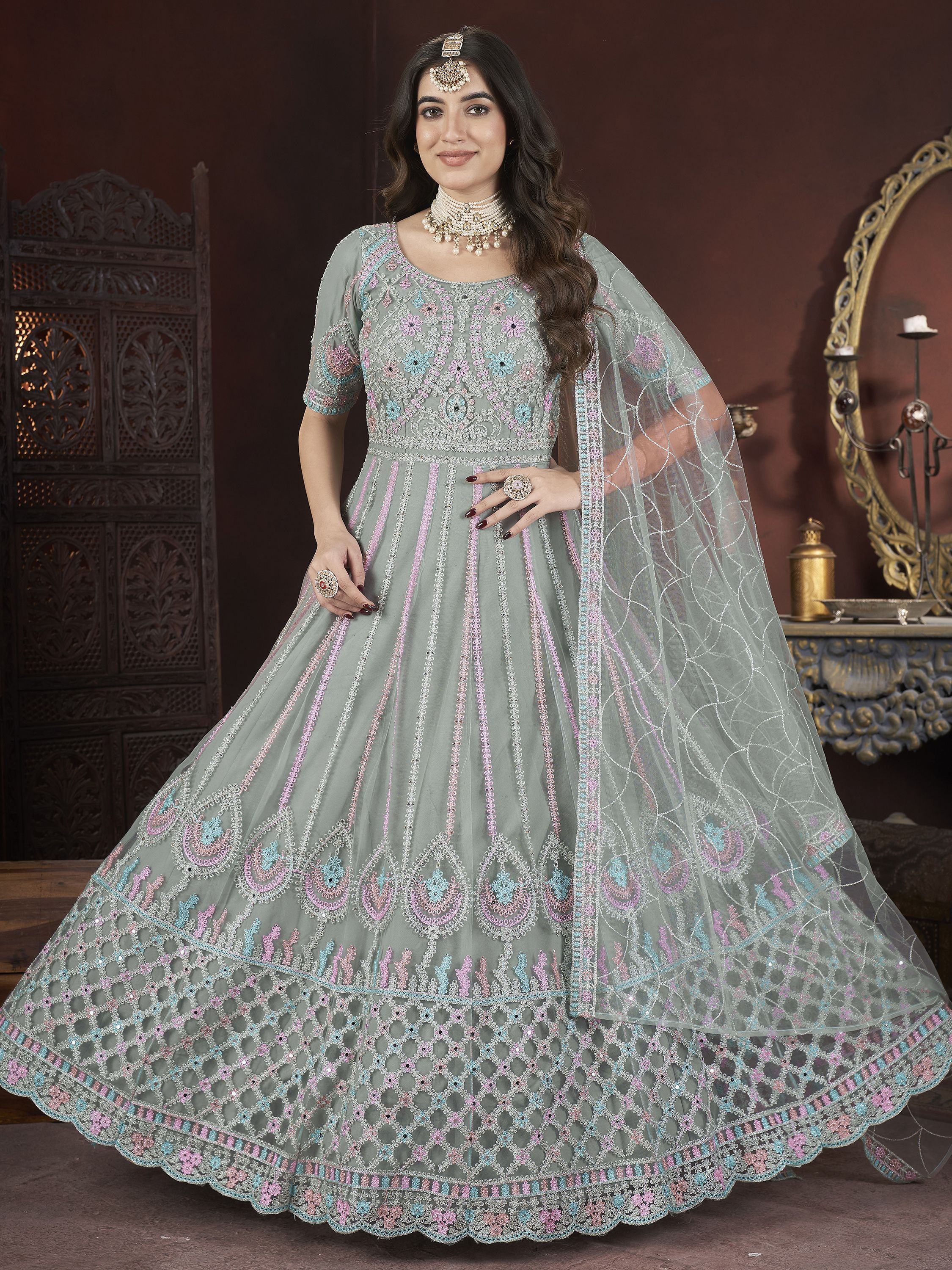 Woman in pastel green embroidered lehenga choli with net dupatta and traditional jewelry