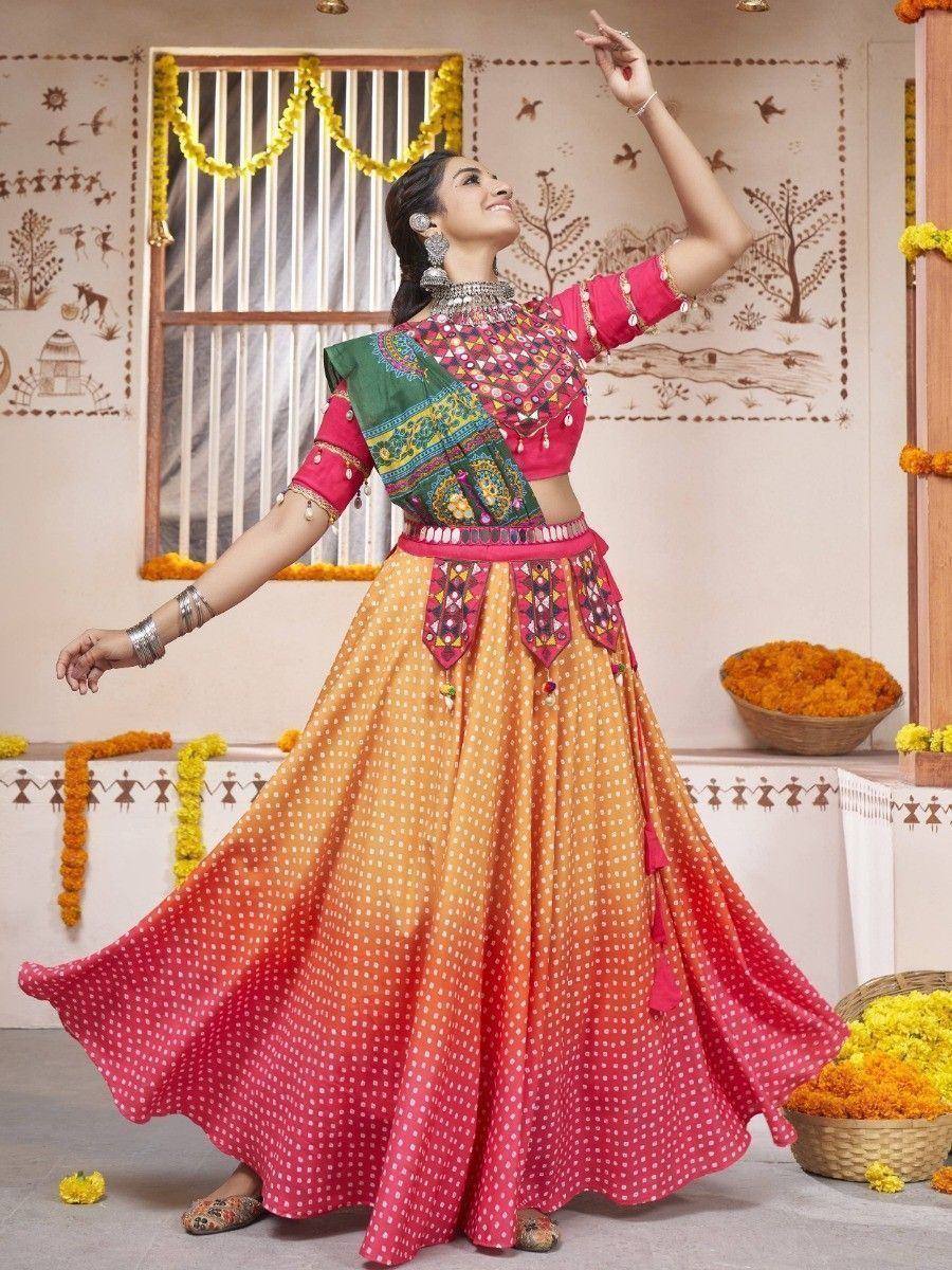Woman in vibrant pink and orange ombre lehenga choli with mirror work, dancing gracefully in festive setting