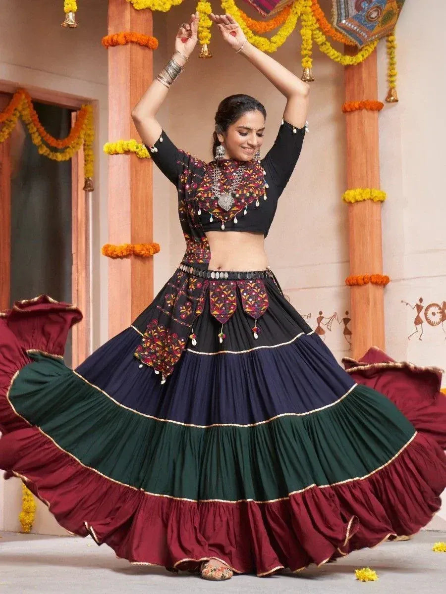 Woman dancing in colorful Indian lehenga choli with embroidered top and tiered skirt, festive marigold decor