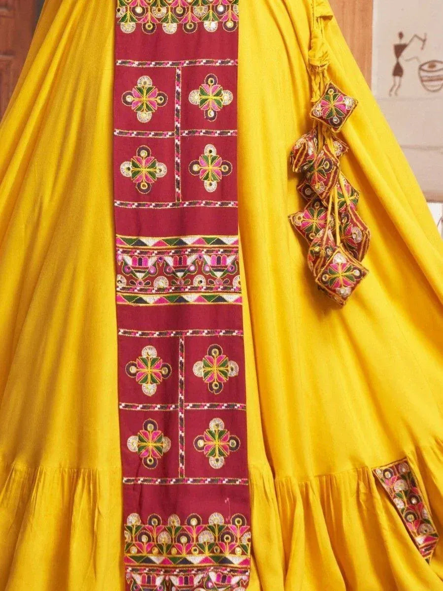 Vibrant yellow ethnic gown with maroon embroidered panel and tassels, perfect for Indian festive occasions