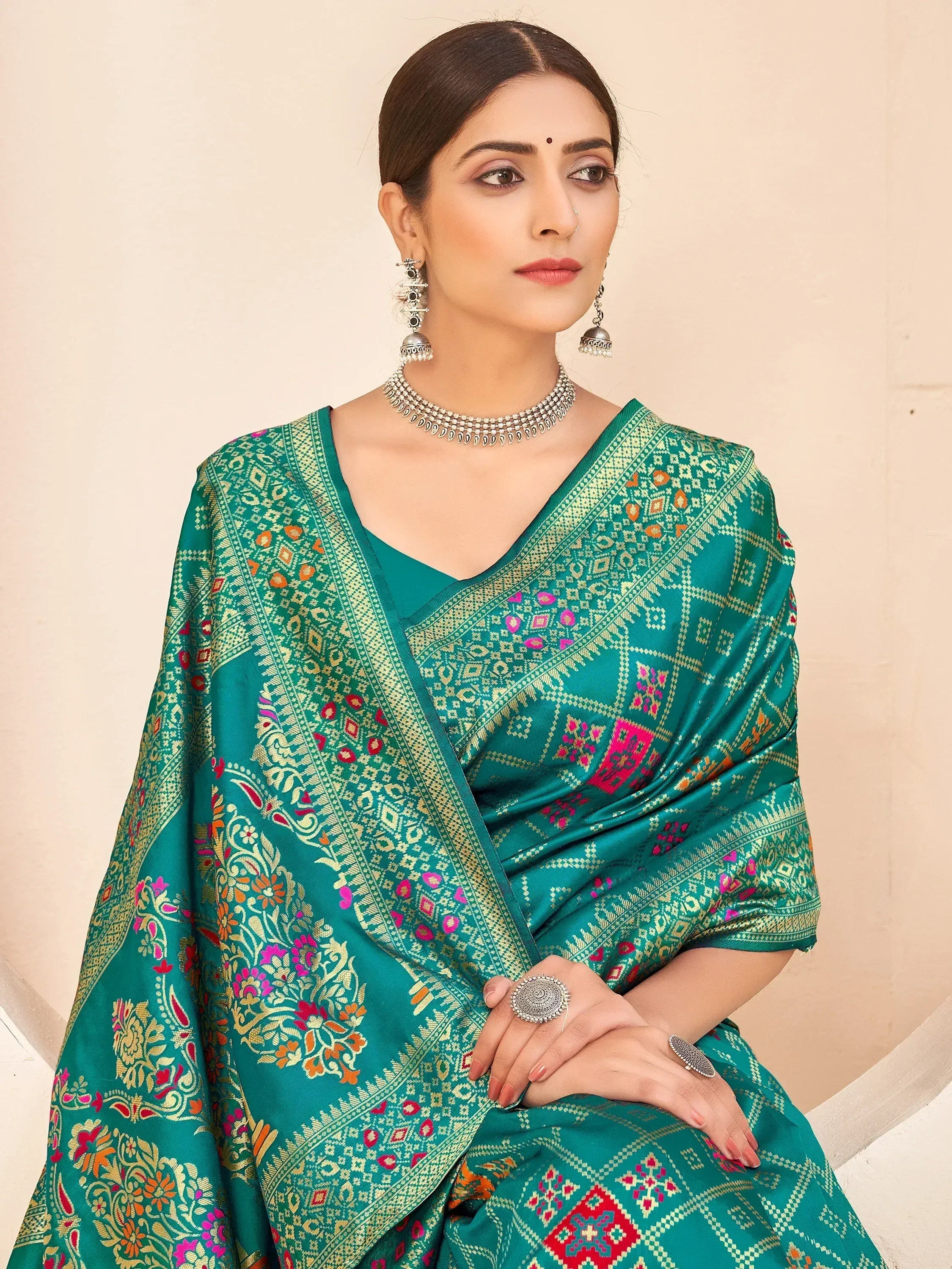 Emerald green designer saree with gold and pink floral embroidery, paired with traditional jewelry