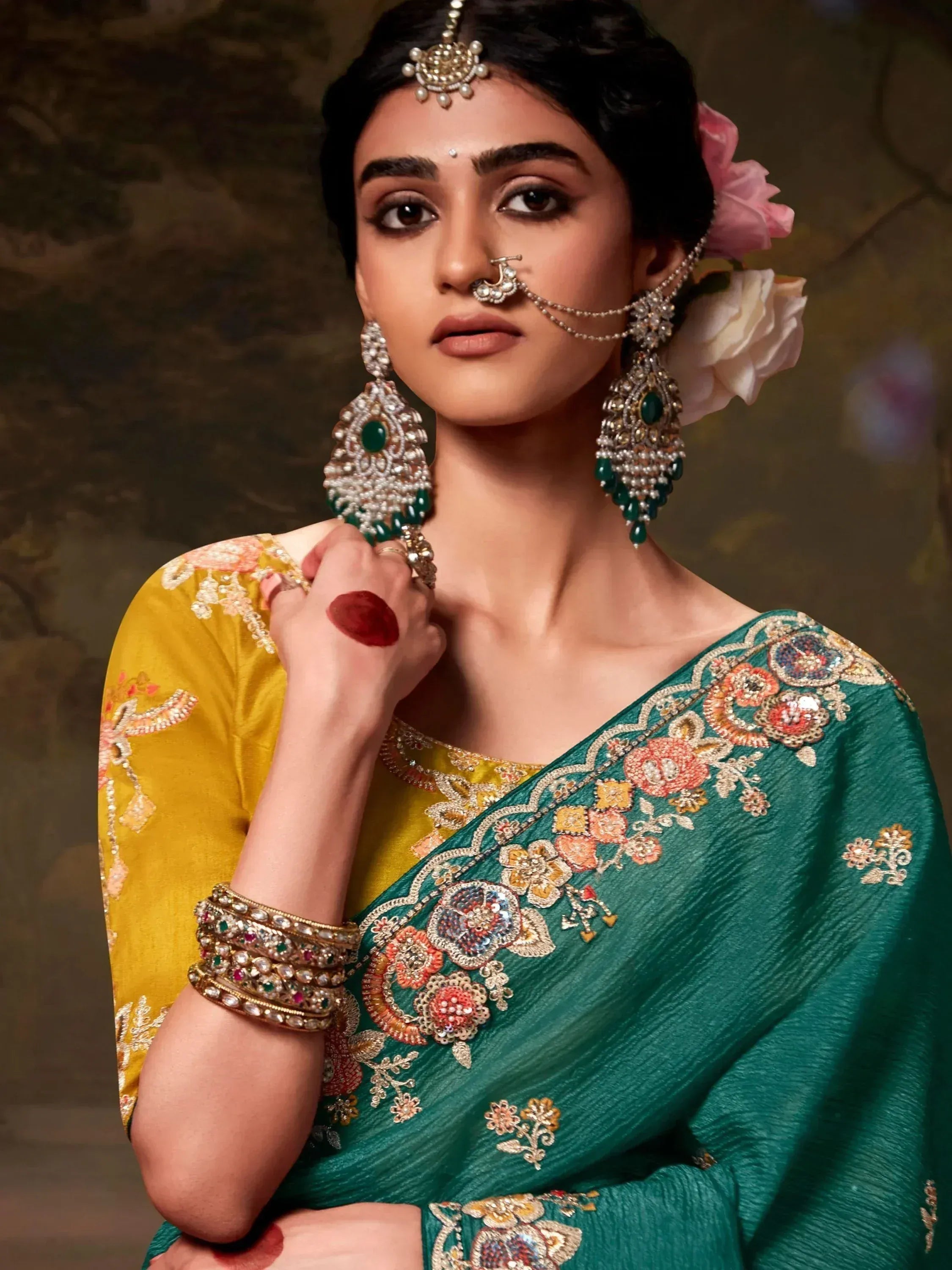 Elegant woman in embroidered green and yellow saree with traditional Indian jewelry and floral hair accessories