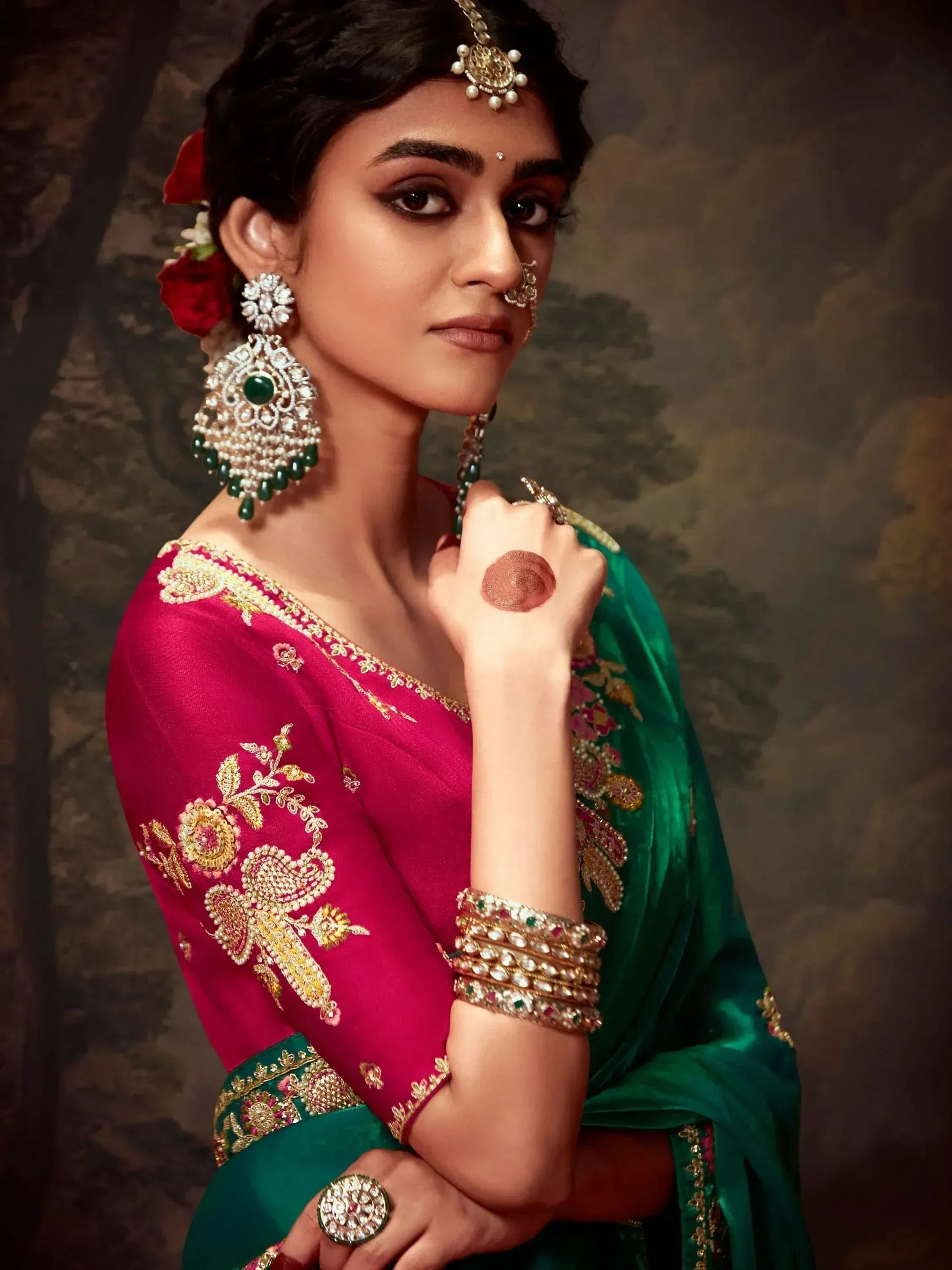 Woman in pink and green embroidered saree with gold jewelry, traditional Indian ethnic wear