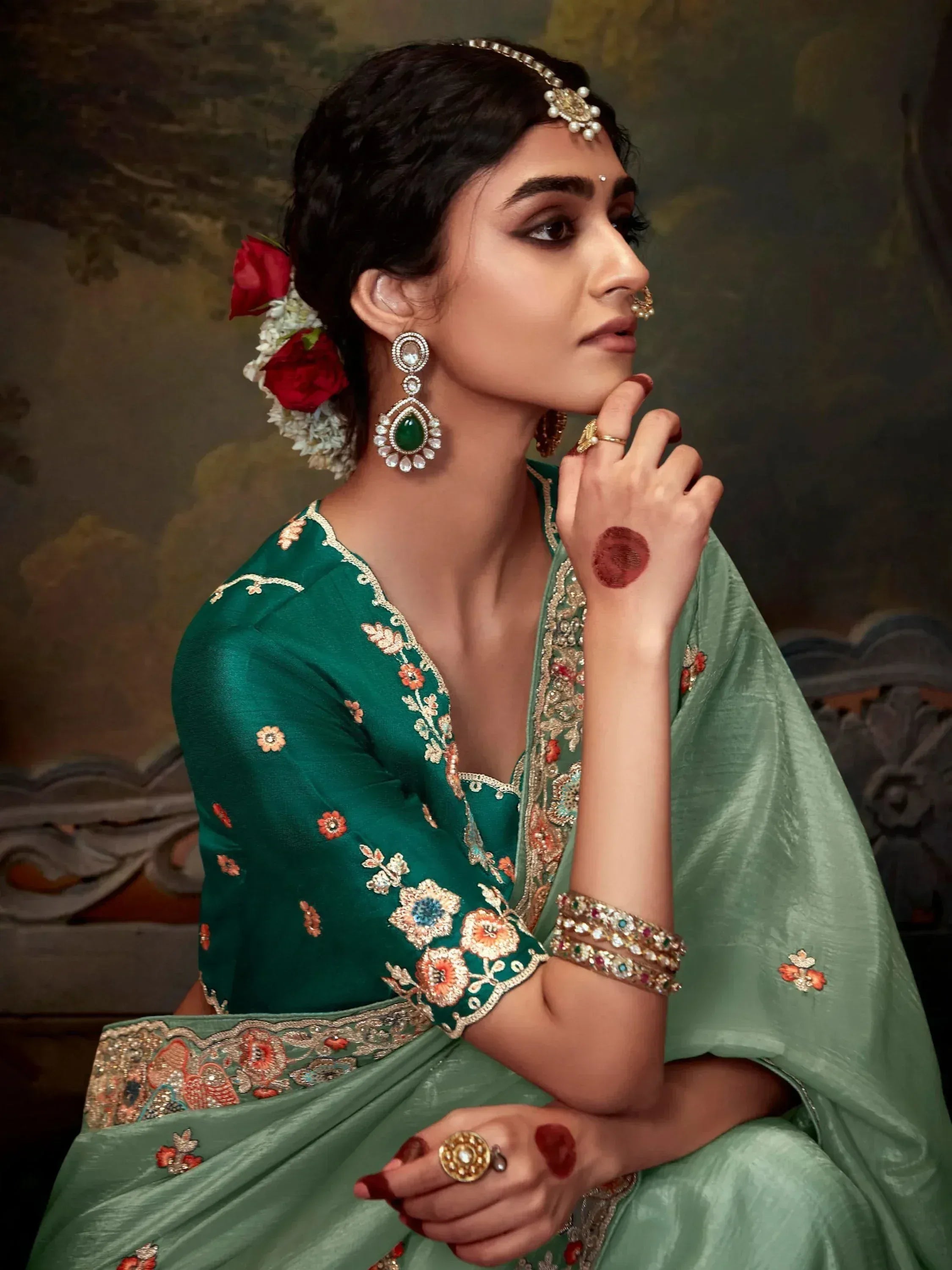 Elegant green embroidered saree with floral design, traditional Indian jewelry, and henna art for festive occasions