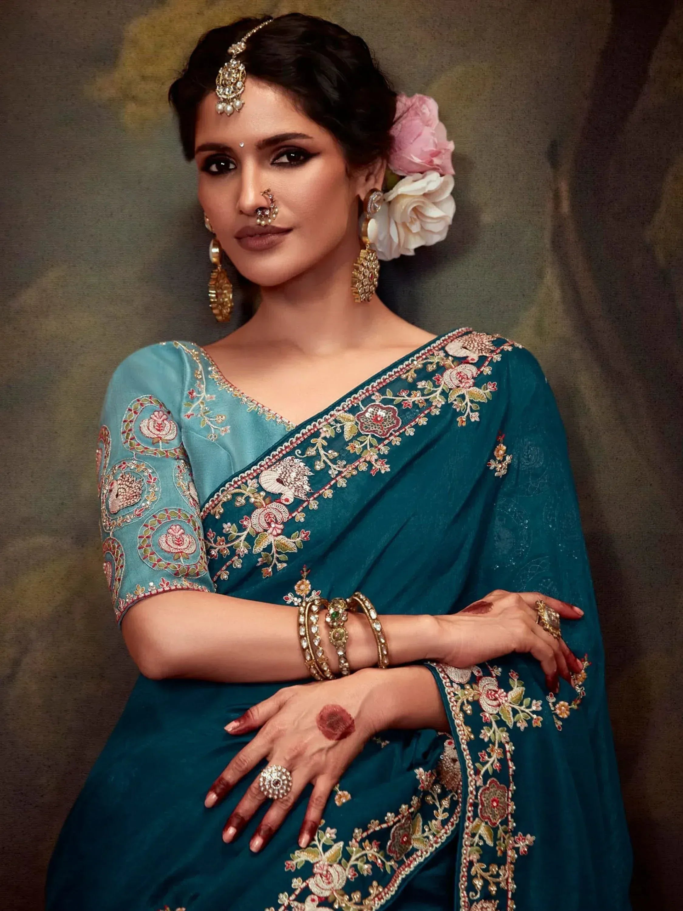 Teal embroidered saree with floral motifs, traditional Indian jewelry, and floral hair accessory for ethnic wear
