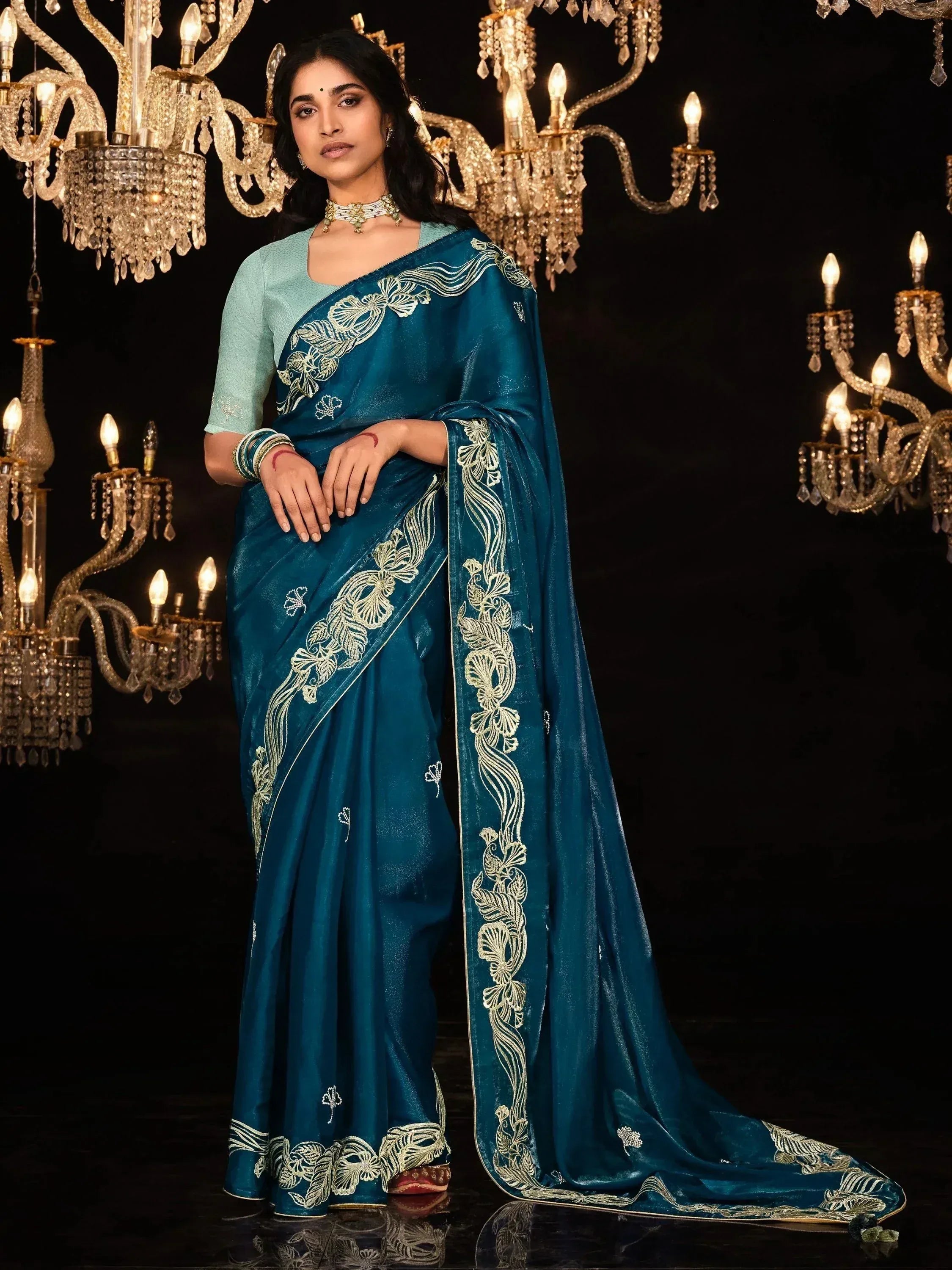 Teal blue embroidered saree with gold floral work, paired with light blue blouse, elegant ethnic wear for women