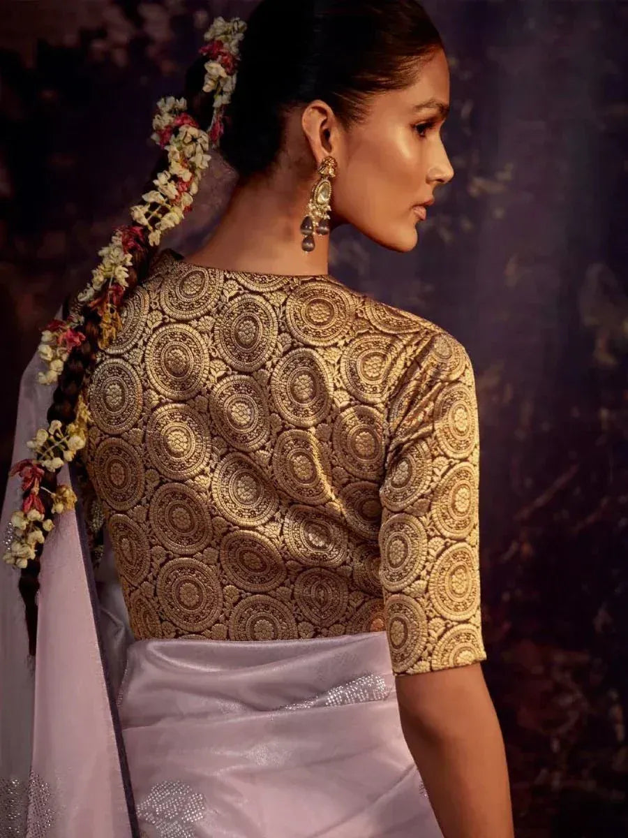 Woman in gold embroidered blouse with floral hair accessory, paired with light purple saree for ethnic wear