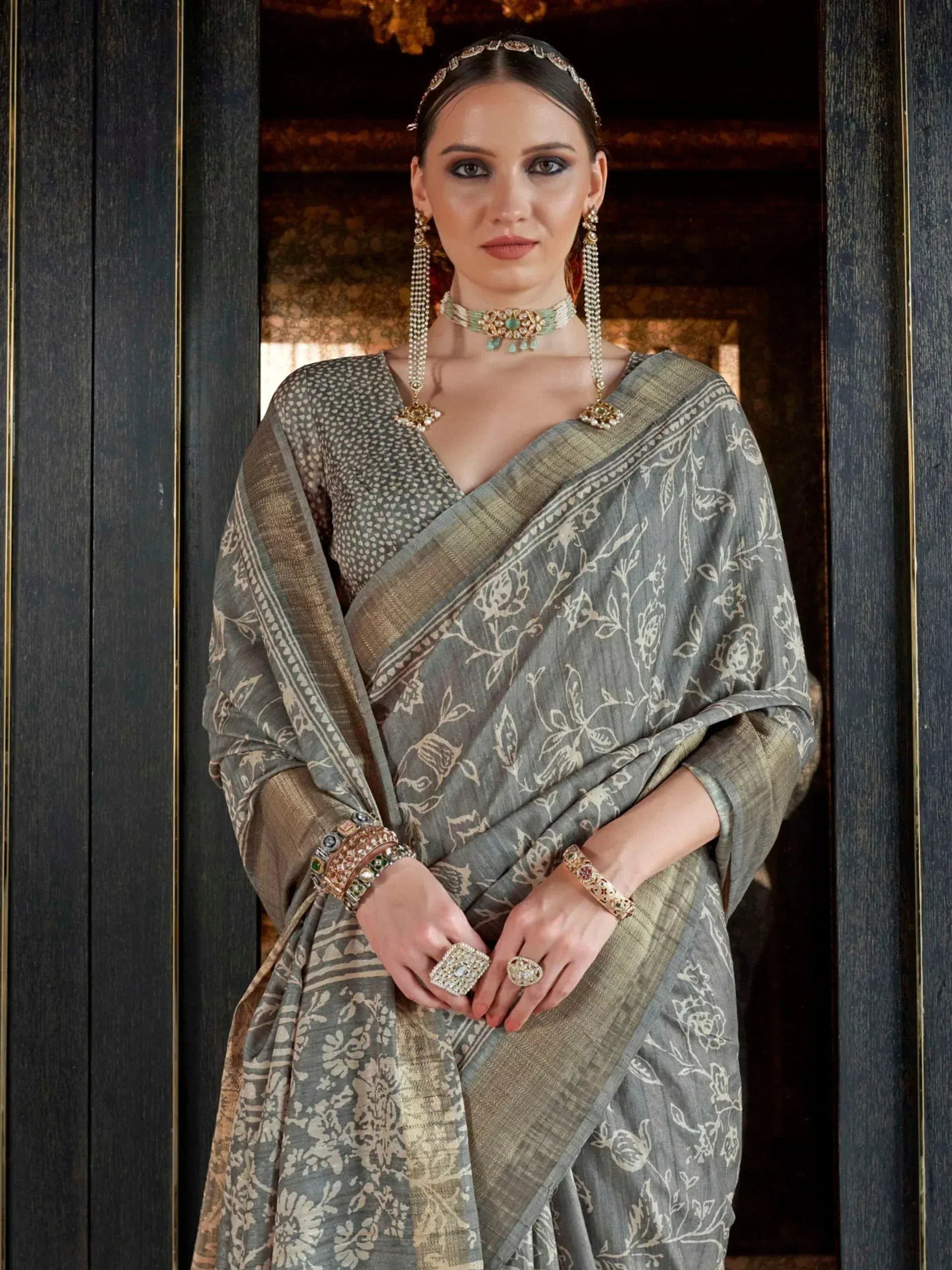 Grey floral printed saree with gold border, paired with traditional Indian jewelry for ethnic wear