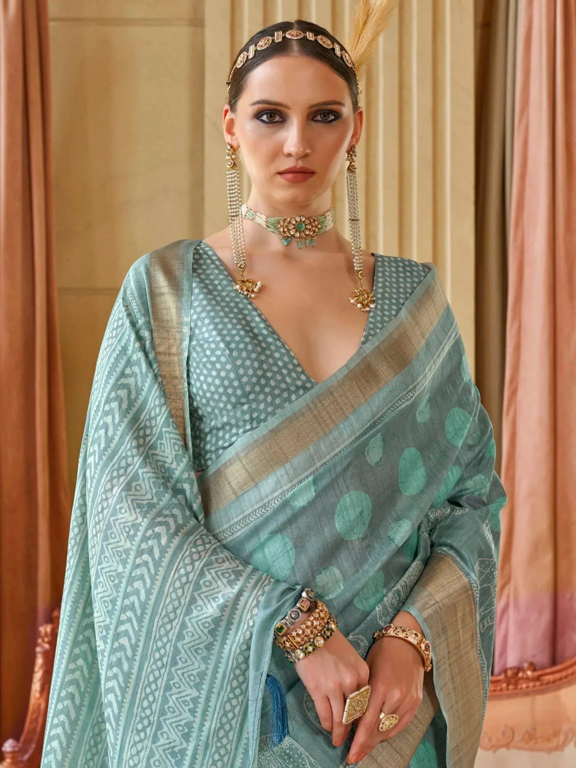 Woman in elegant mint green saree with gold border, traditional jewelry, and ethnic print for festive occasions.
