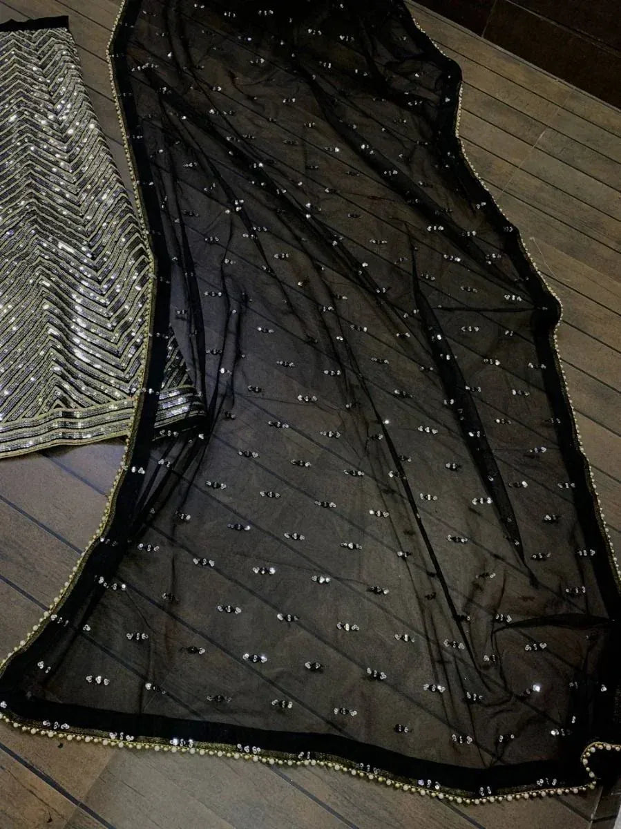 Black sheer dupatta with silver sequins and gold trim, paired with embellished lehenga choli
