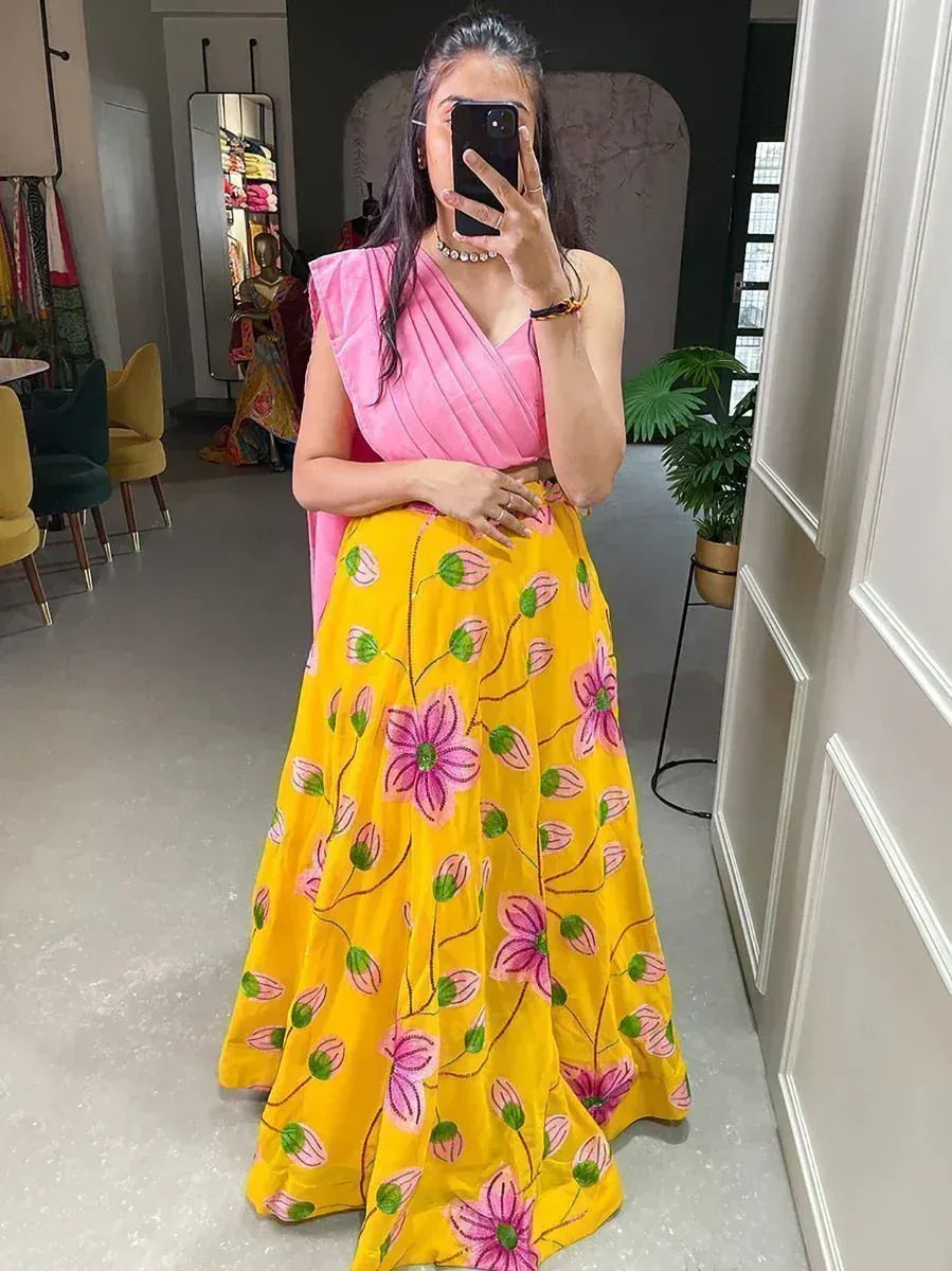 Woman in pink top and yellow floral lehenga, taking mirror selfie in boutique