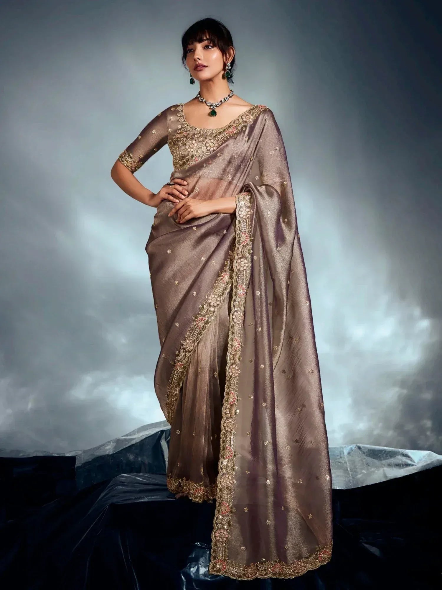 Elegant brown saree with gold embroidery and floral detailing, paired with matching blouse and jewelry.