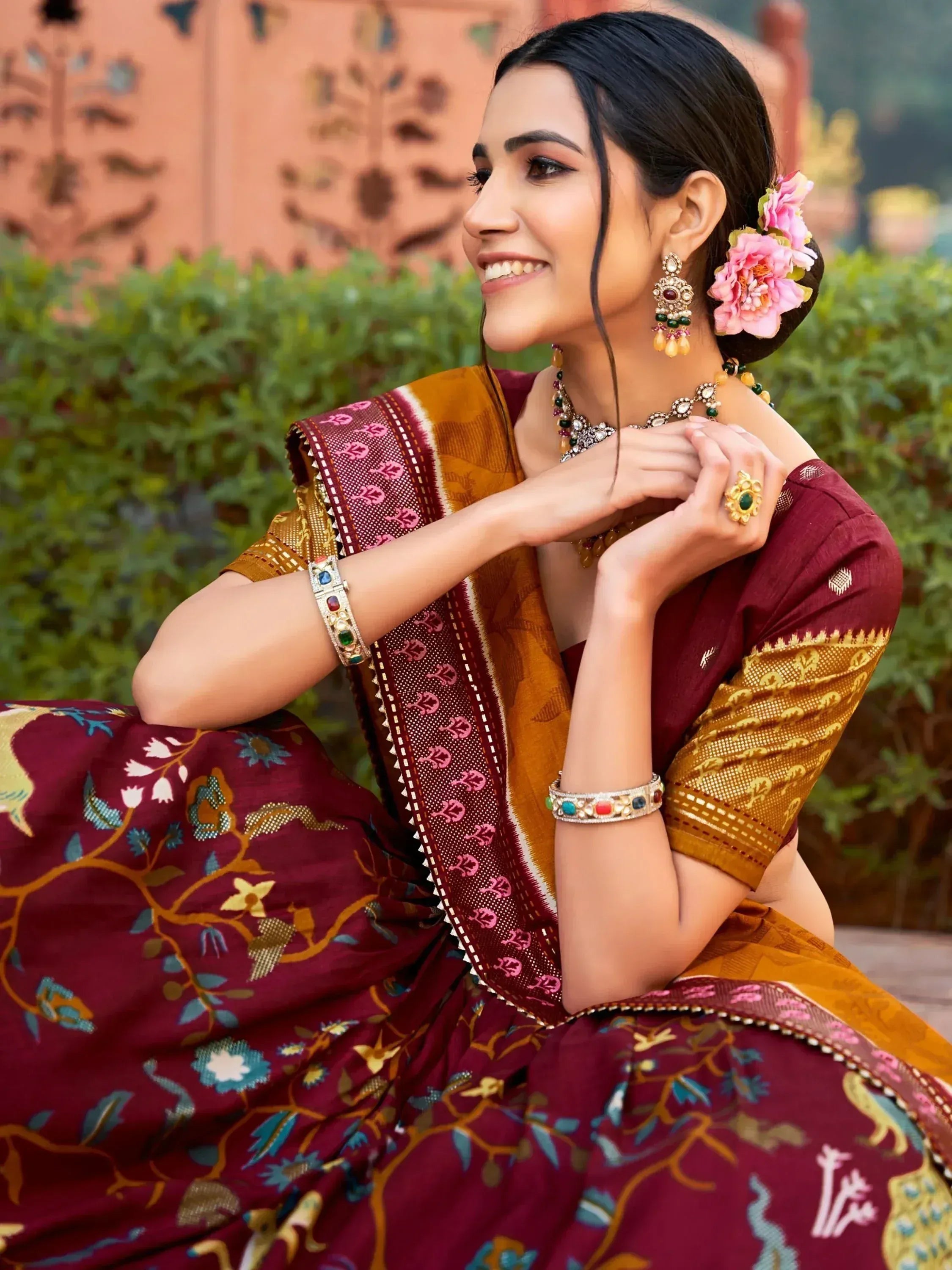 Woman in maroon and gold floral saree with traditional jewelry, perfect for ethnic occasions