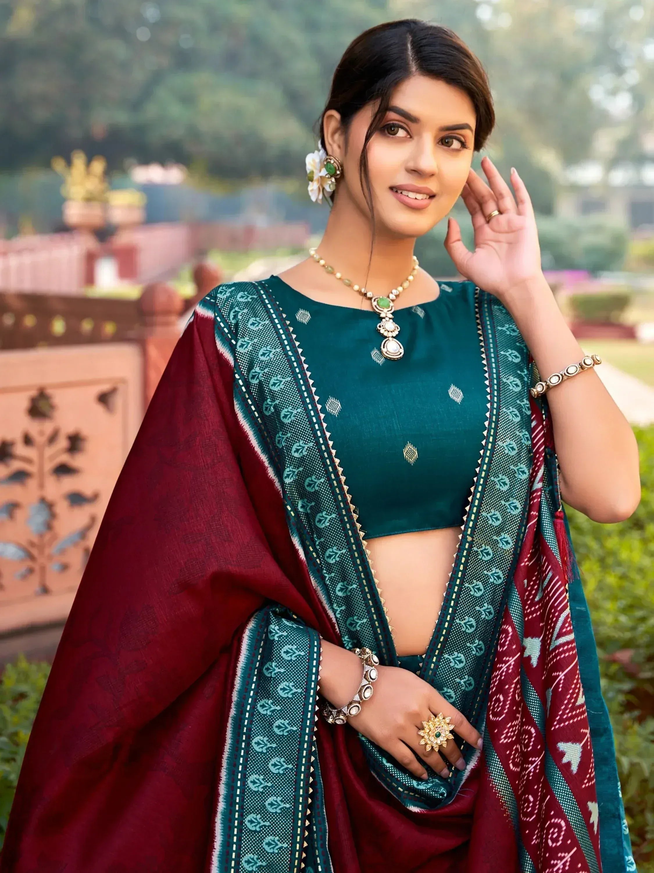Woman in teal and maroon ethnic saree with gold jewelry, perfect for Indian occasions
