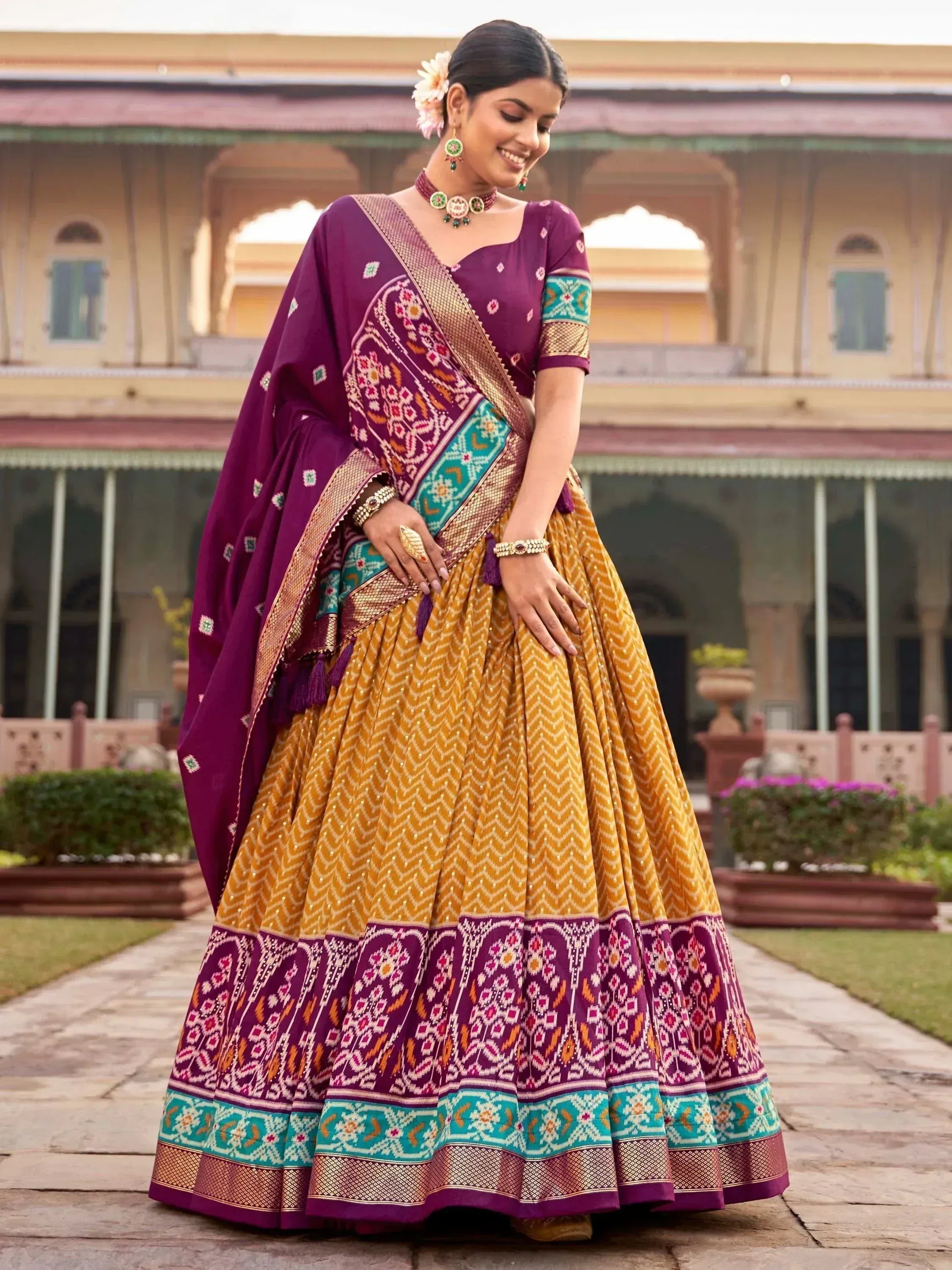 Woman in purple and gold designer lehenga choli with floral dupatta, traditional Indian ethnic wear