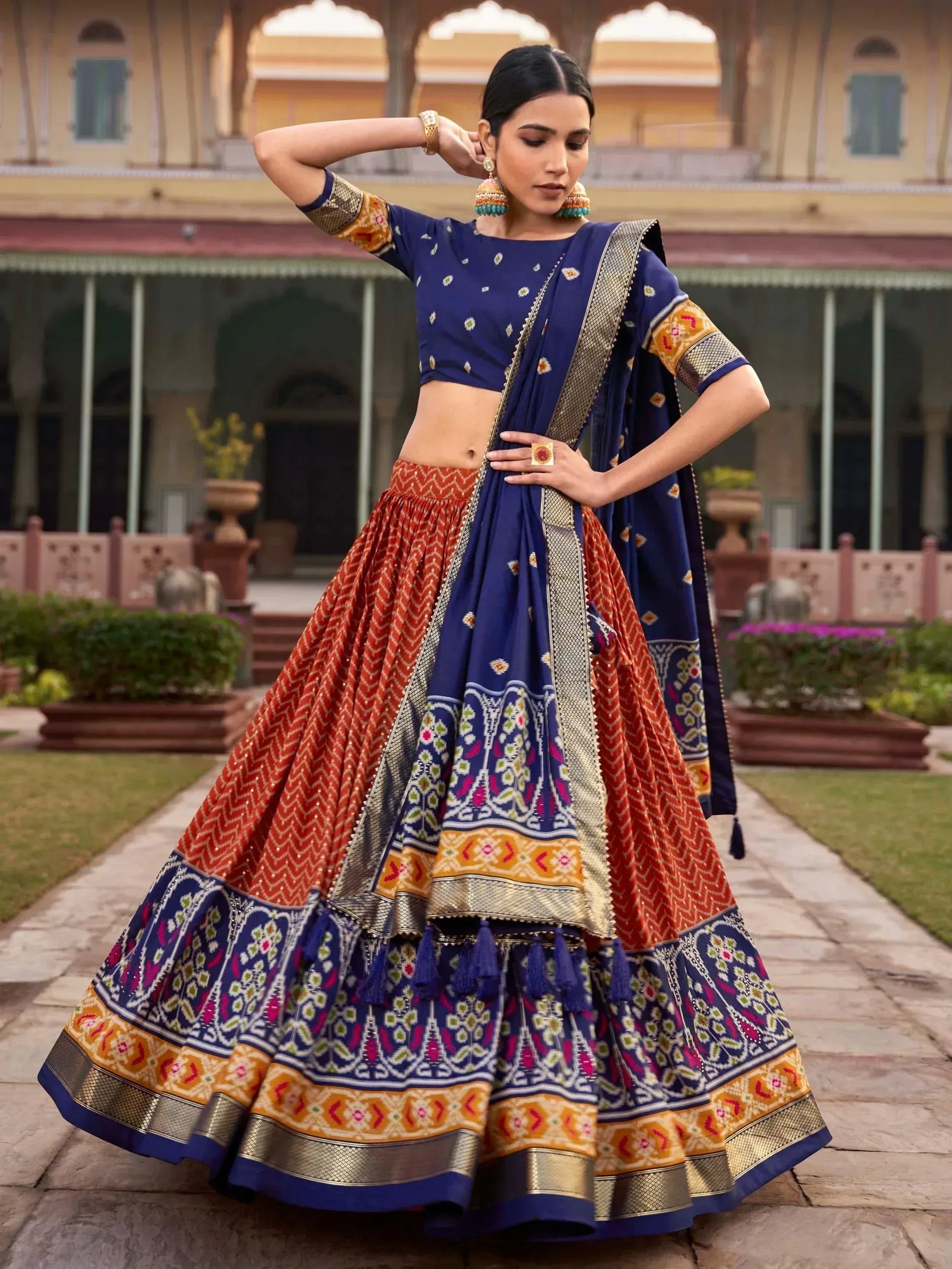 Blue and orange designer lehenga choli with intricate embroidery and gold border, perfect for Indian ethnic wear.