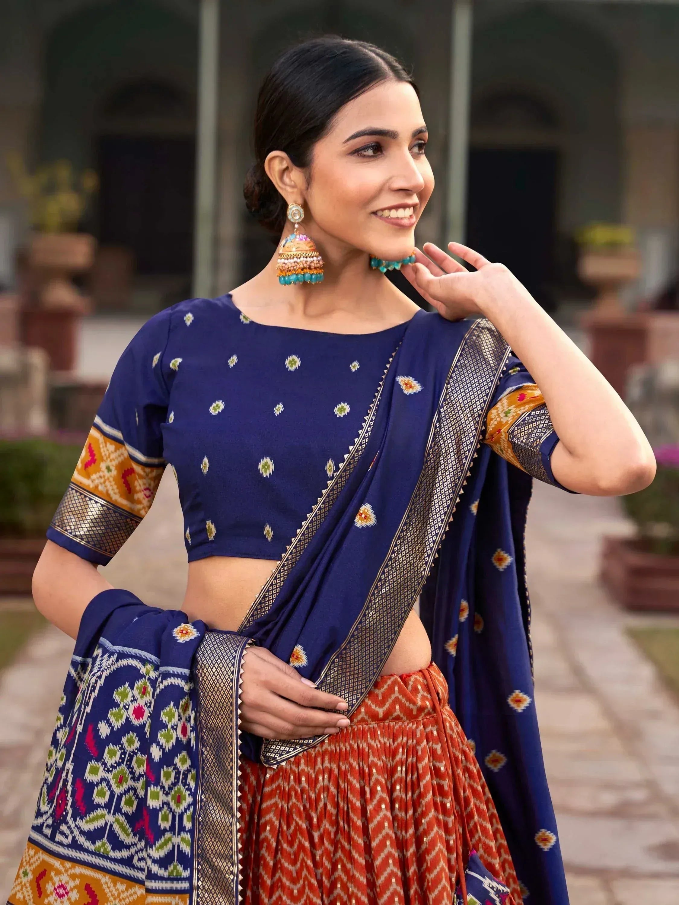 Woman in blue printed lehenga choli with orange skirt and gold border, traditional Indian ethnic wear