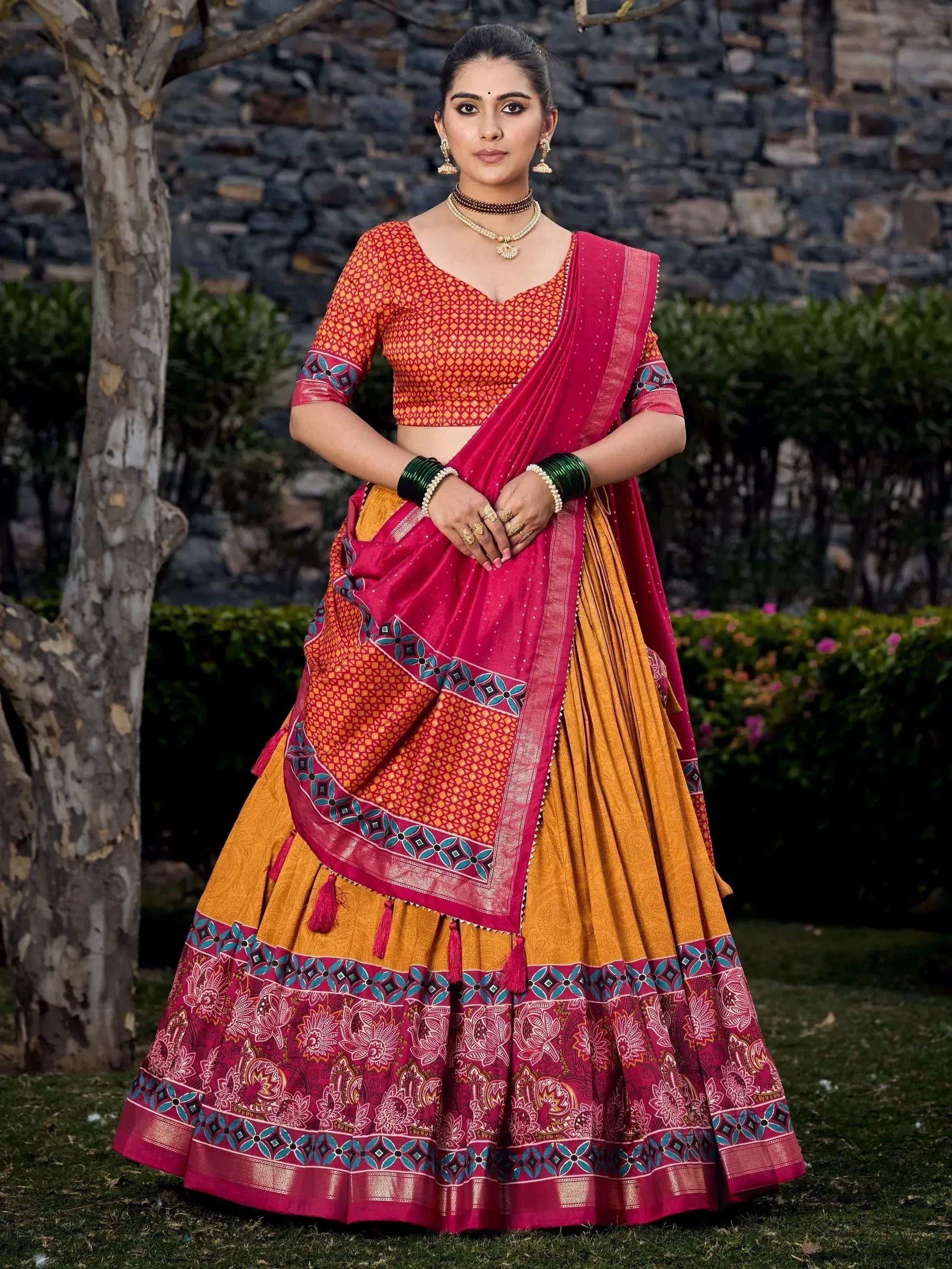 Woman in vibrant Indian lehenga choli with pink and orange print, perfect for ethnic occasions