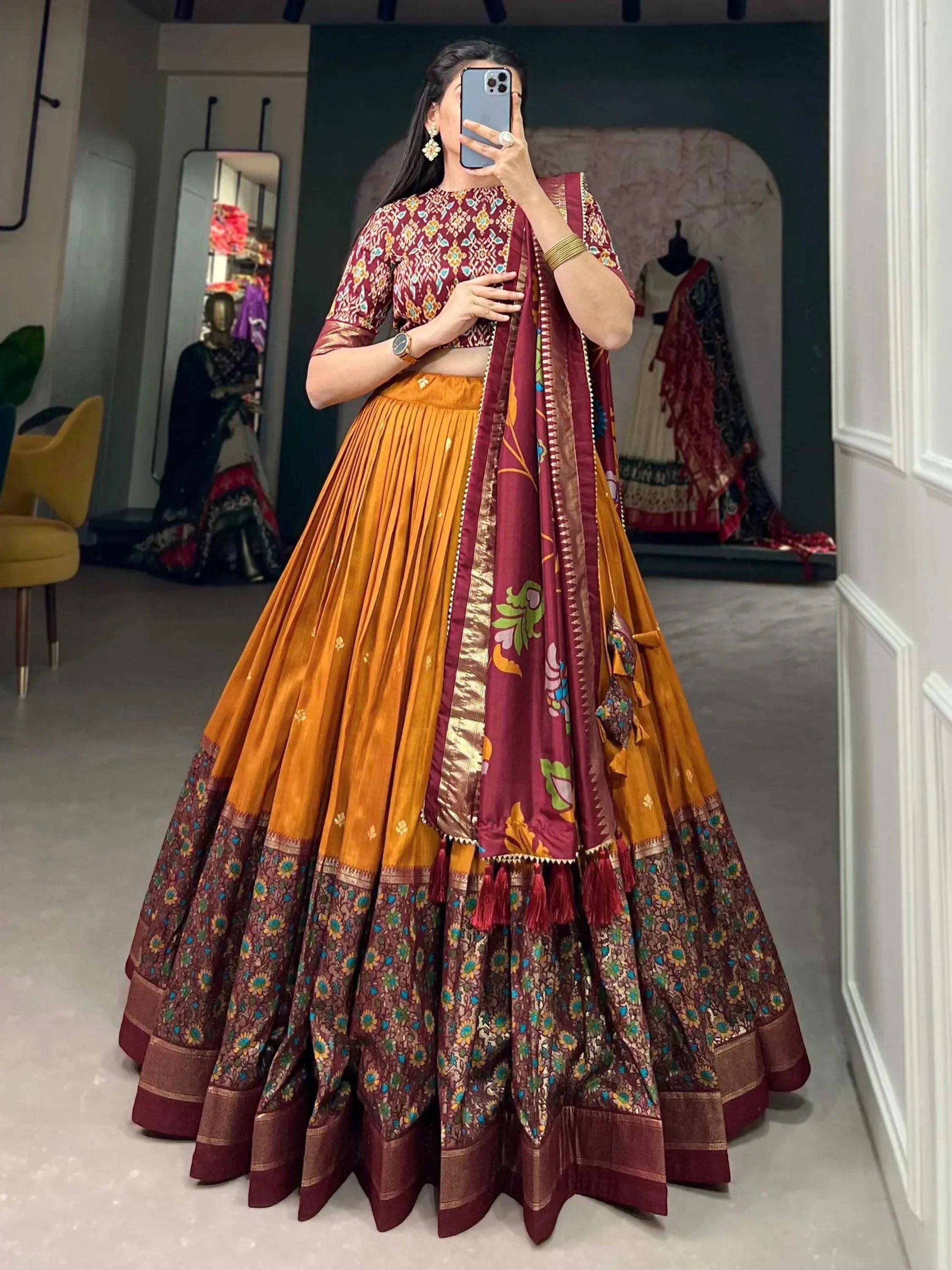Woman in maroon and mustard designer lehenga choli with floral print and tassels, perfect for Indian ethnic wear