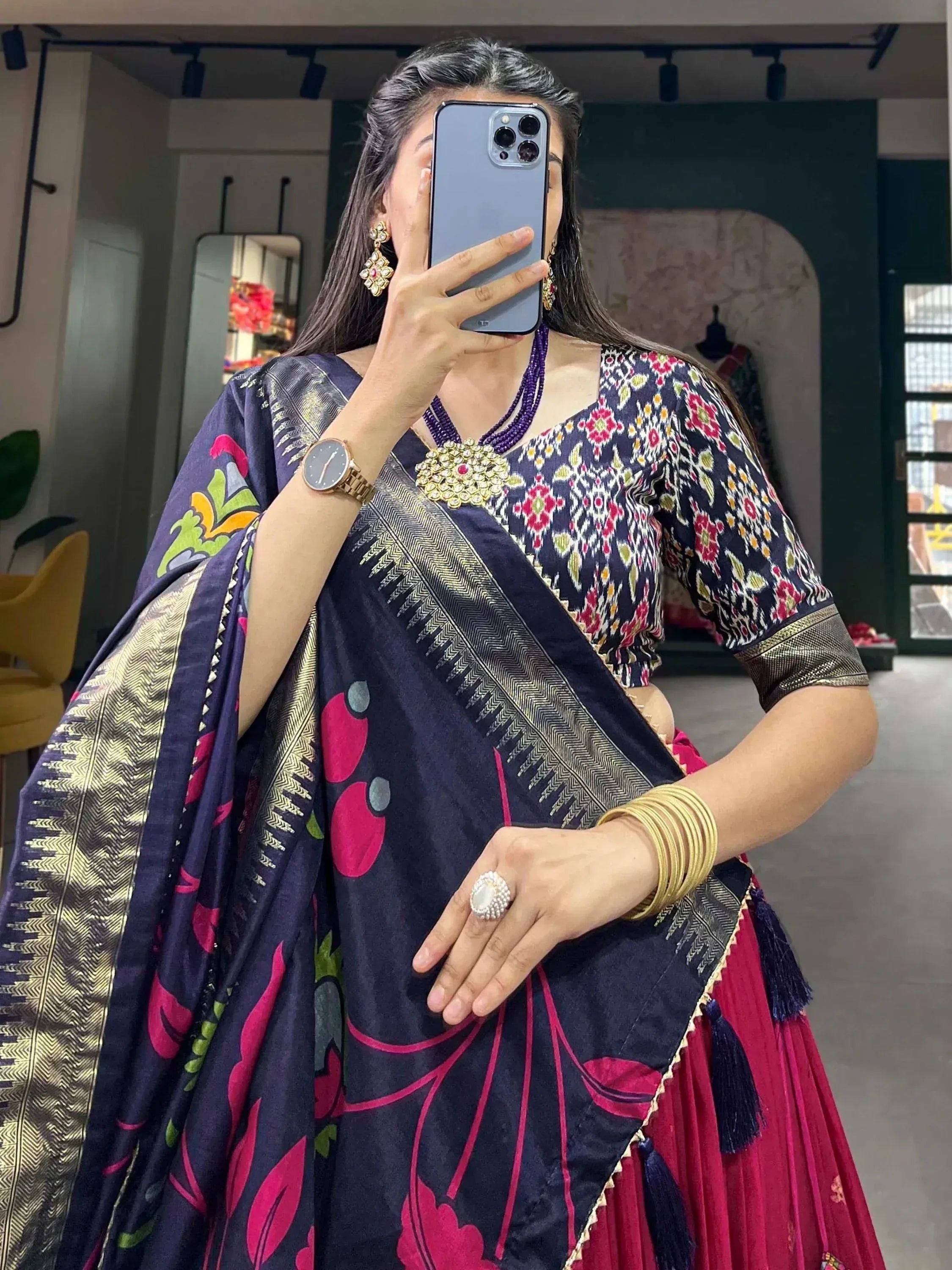 Woman in navy floral saree with gold border, paired with embroidered blouse and traditional jewelry
