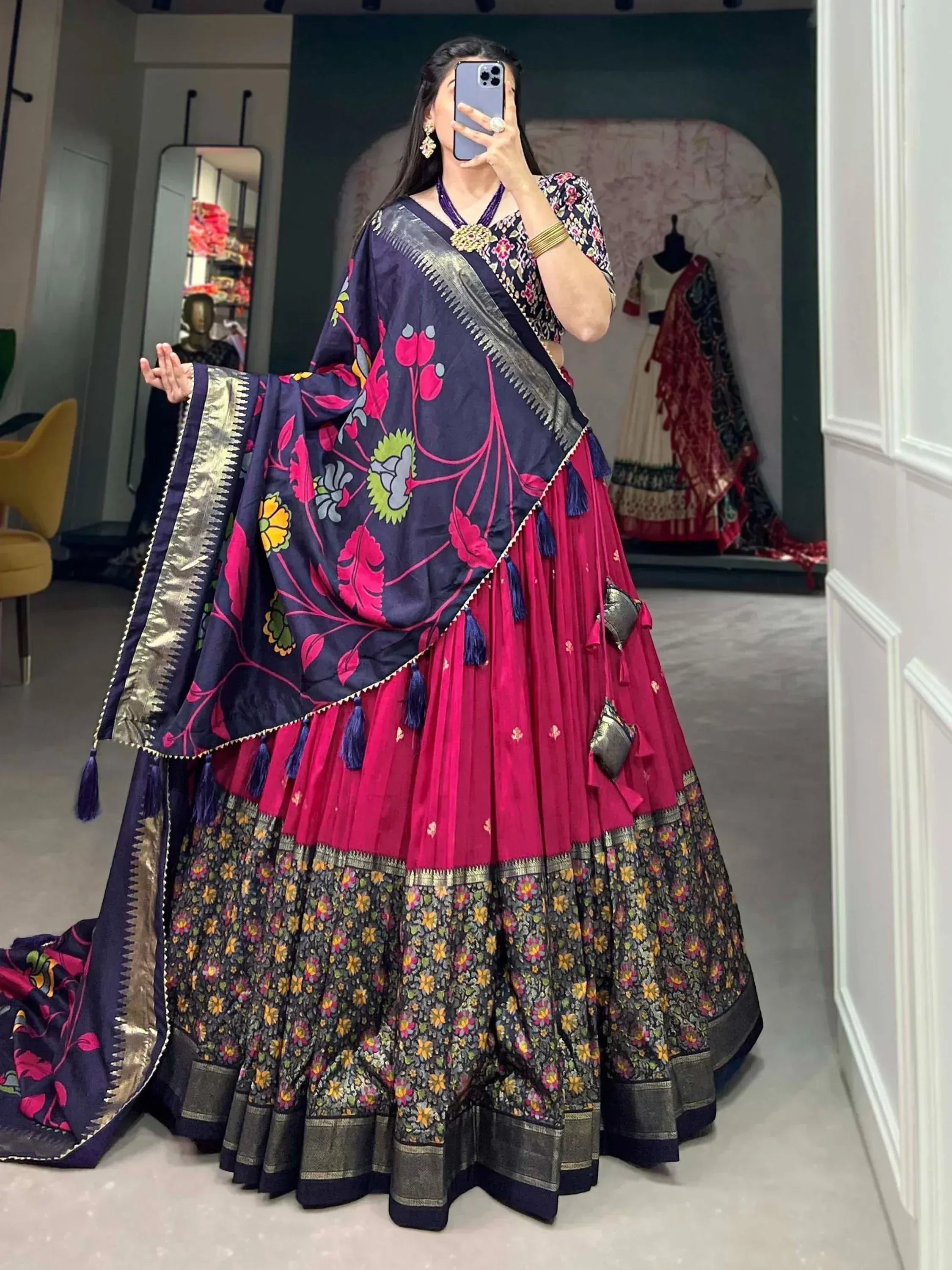 Woman in vibrant floral lehenga choli with navy dupatta, showcasing Indian ethnic wear for festive occasions.