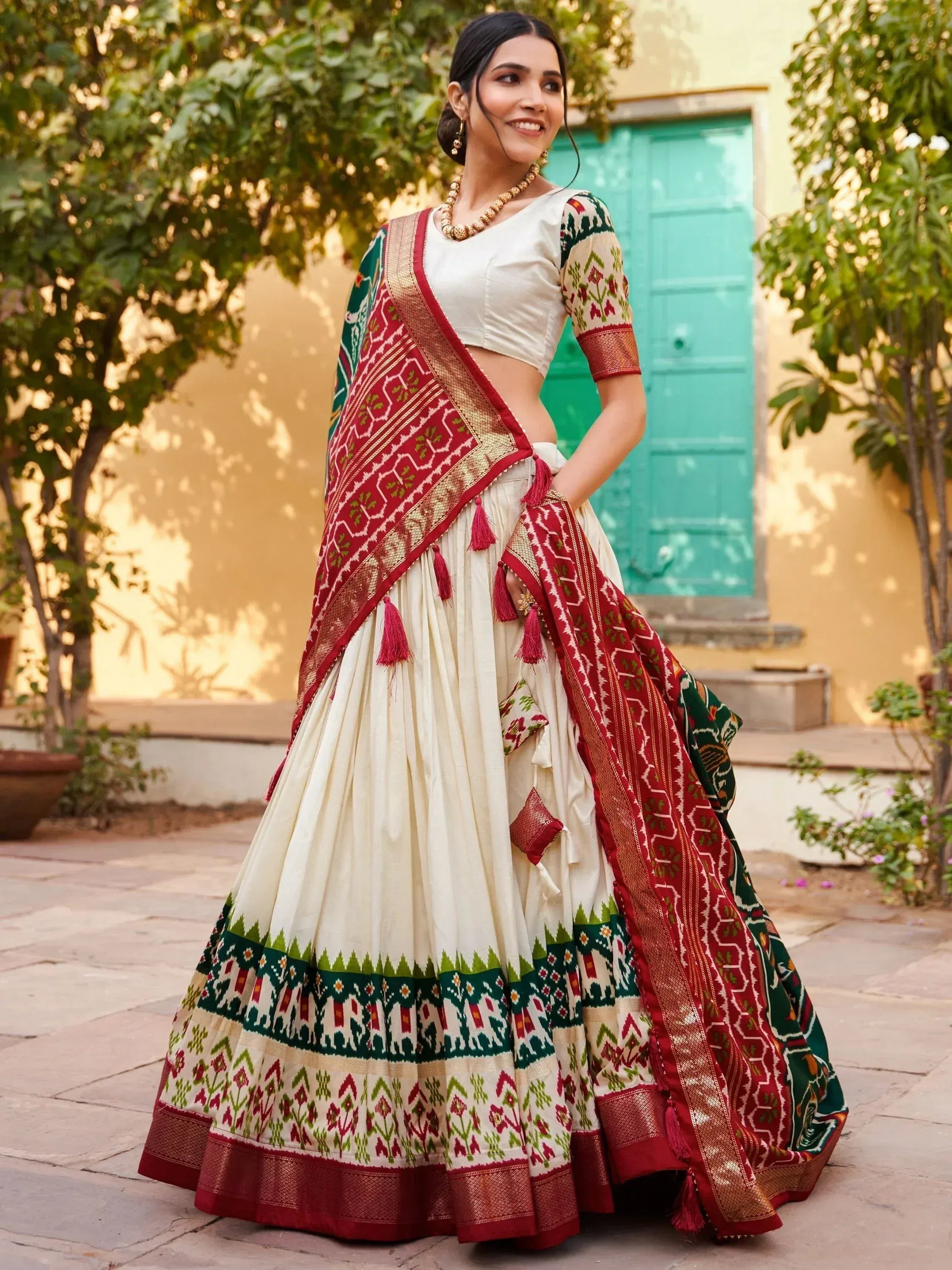 Woman in cream lehenga choli with red green ikat print and tassels, perfect for Indian ethnic occasions