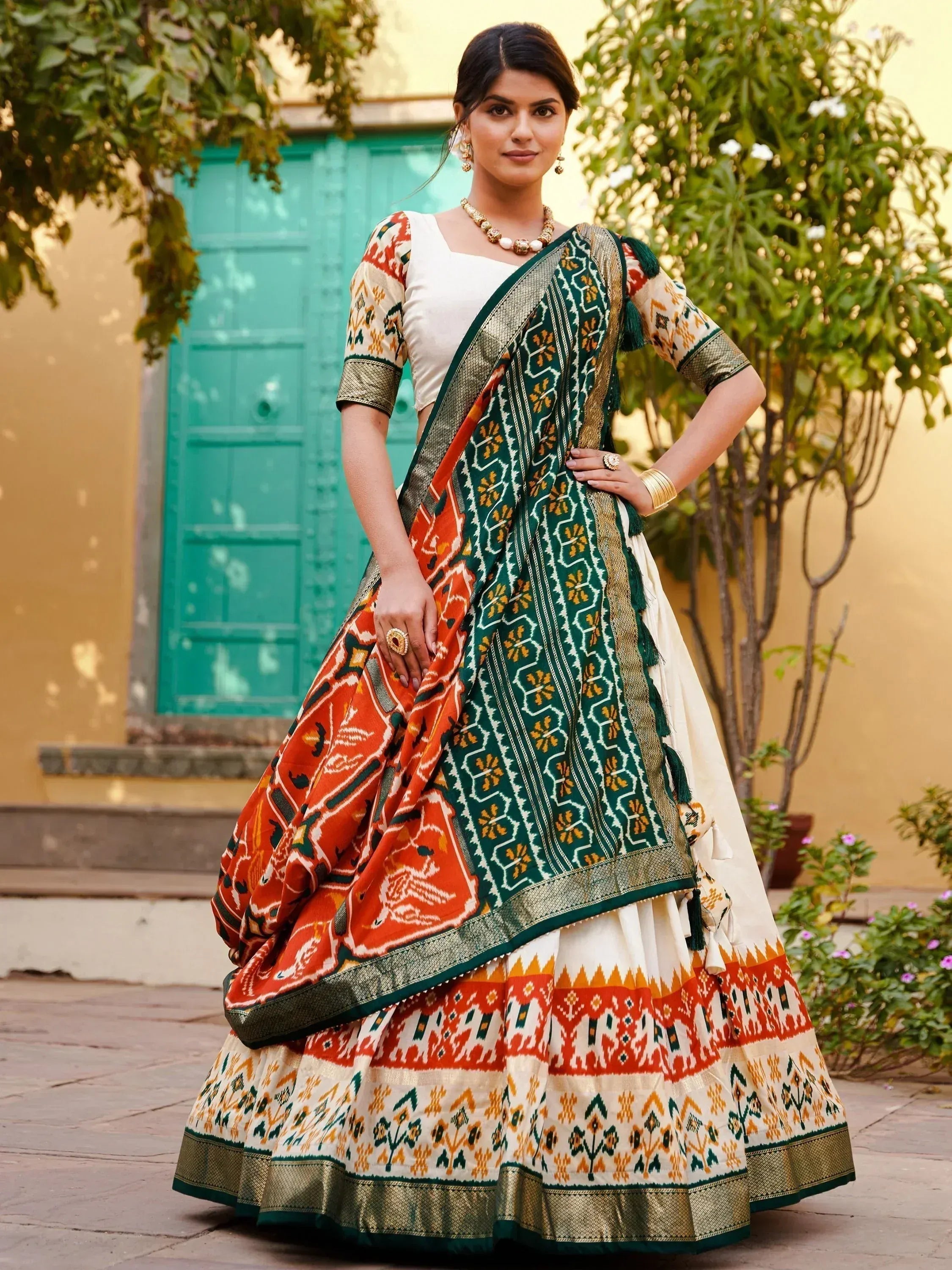 Woman in vibrant ethnic lehenga choli with green, orange, and gold ikat patterns, perfect for Indian festivals
