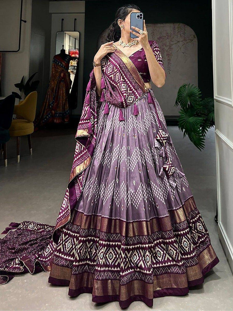 Purple ethnic lehenga choli with geometric print and gold border, perfect for Indian weddings or festive occasions.