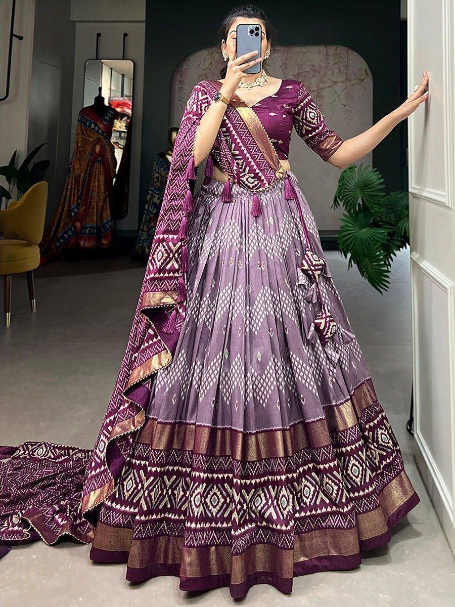 Purple ethnic lehenga choli with geometric print, tassels, and gold border, perfect for weddings or festivals