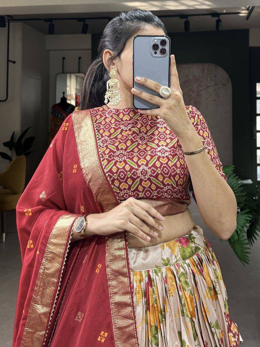 Woman in red printed lehenga choli with floral skirt and gold border, taking mirror selfie