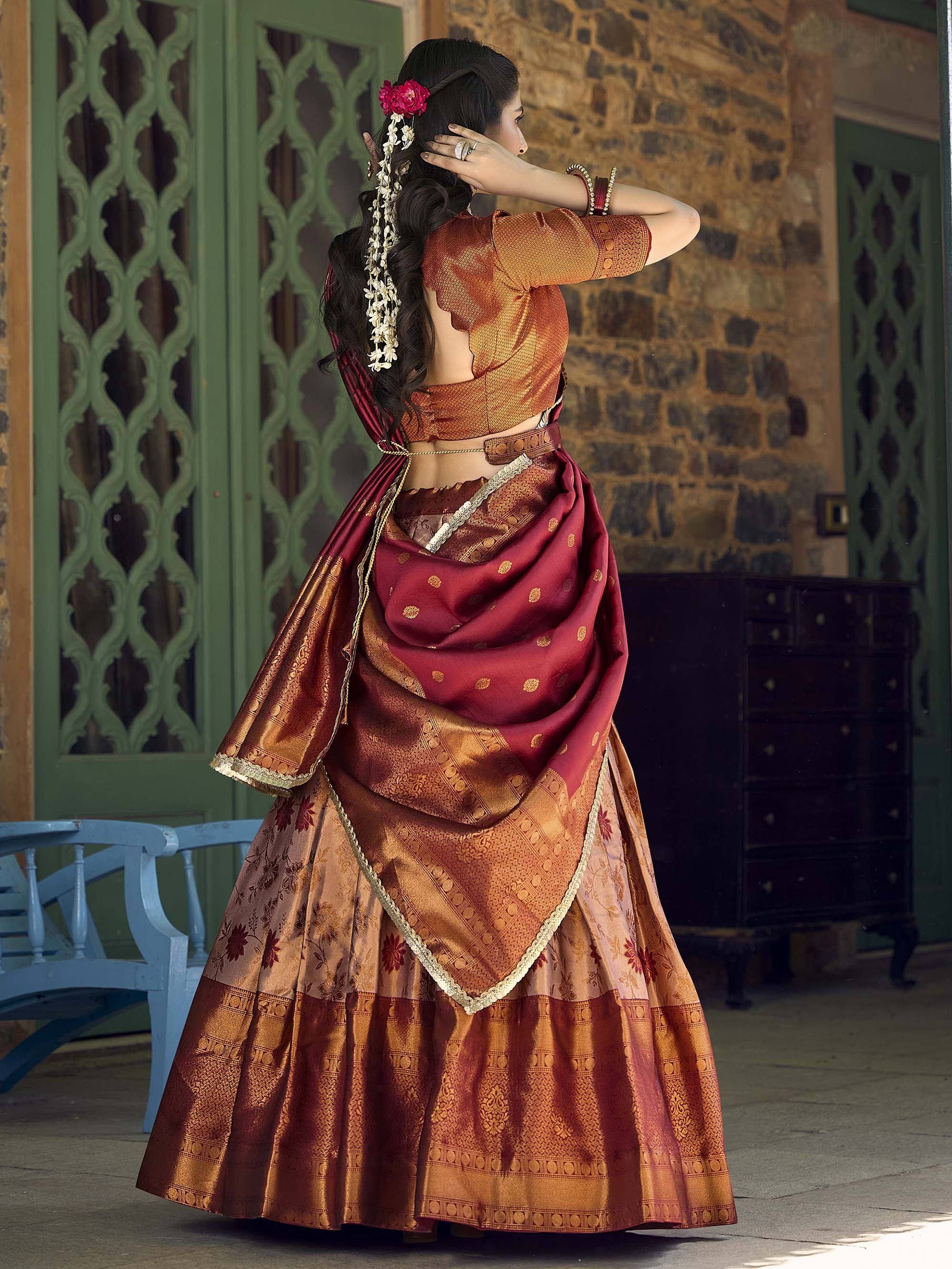Woman in maroon and gold designer lehenga choli with floral hair accessory, traditional Indian ethnic wear