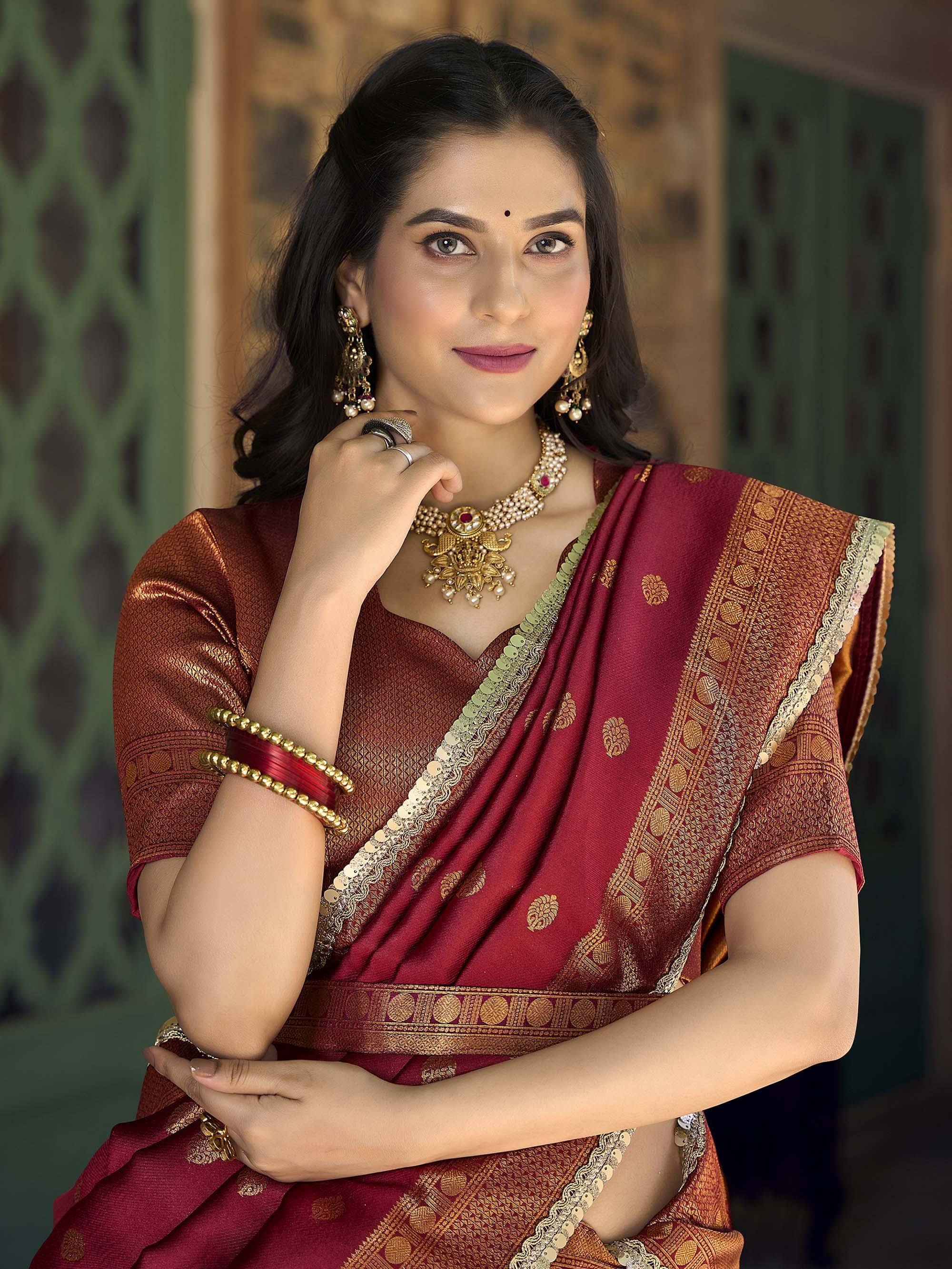Woman in maroon and gold designer saree with traditional jewelry, perfect for Indian ethnic occasions