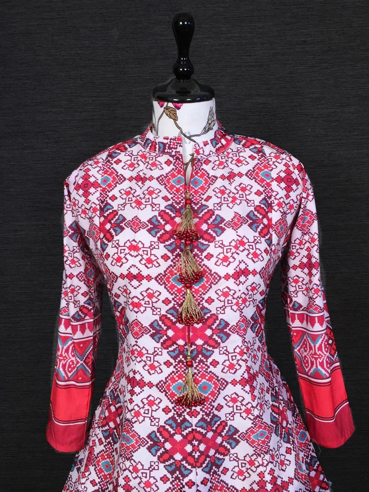 Red and white printed ethnic kurta with tassels, mandarin collar, and full sleeves on mannequin