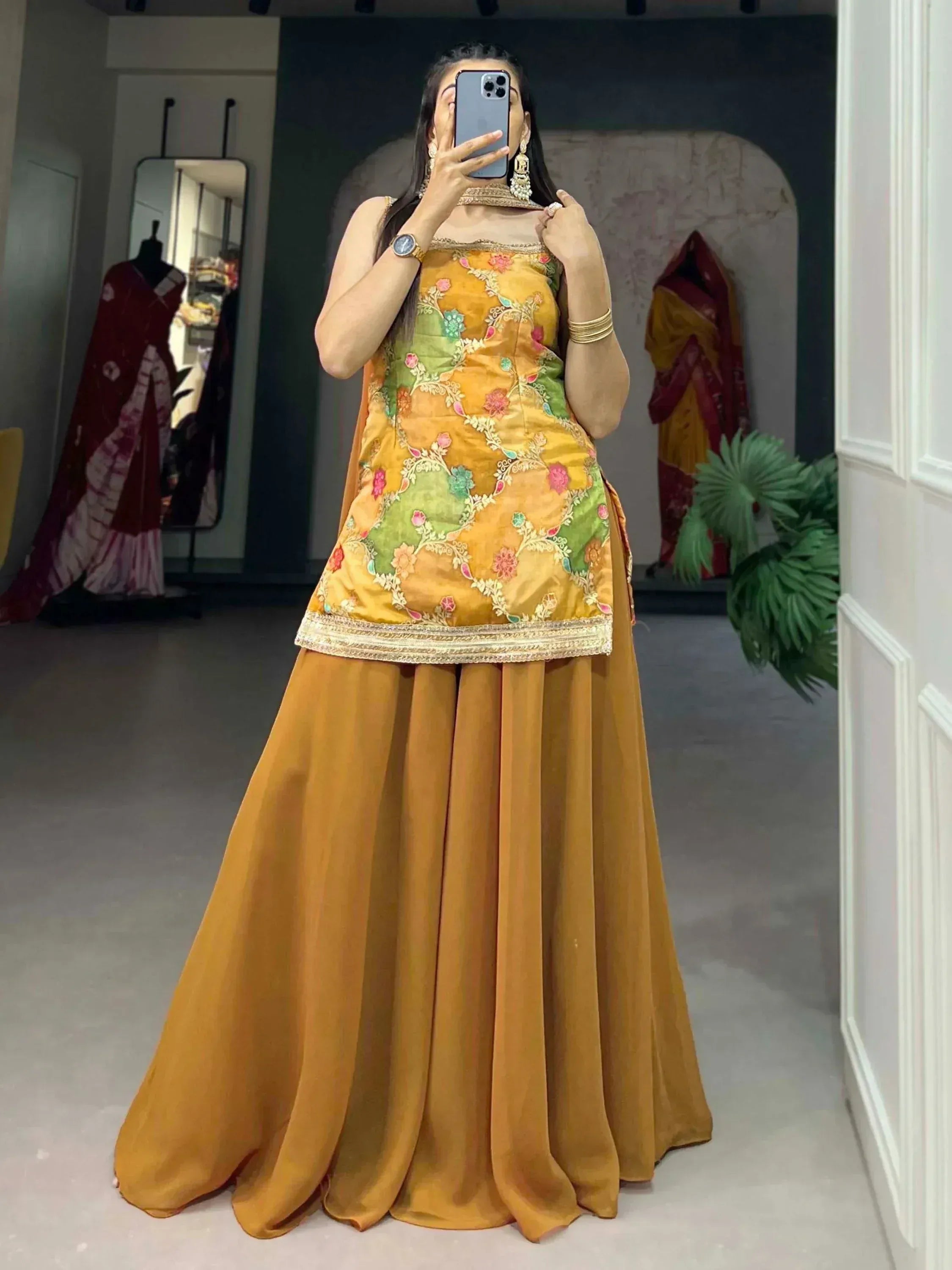 Woman in mustard yellow floral embroidered ethnic gown with matching skirt, perfect for Indian occasions.