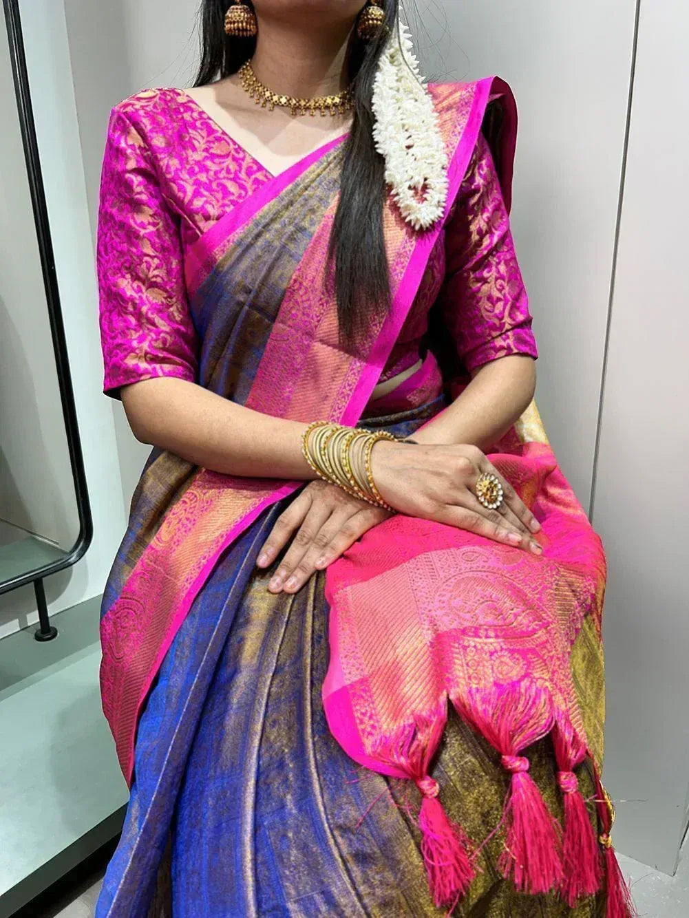 Vibrant pink and blue designer saree with gold embroidery, tassels, and traditional jewelry for ethnic wear