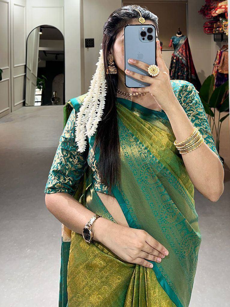 Woman in green and gold designer saree with floral hair accessory, traditional Indian ethnic wear